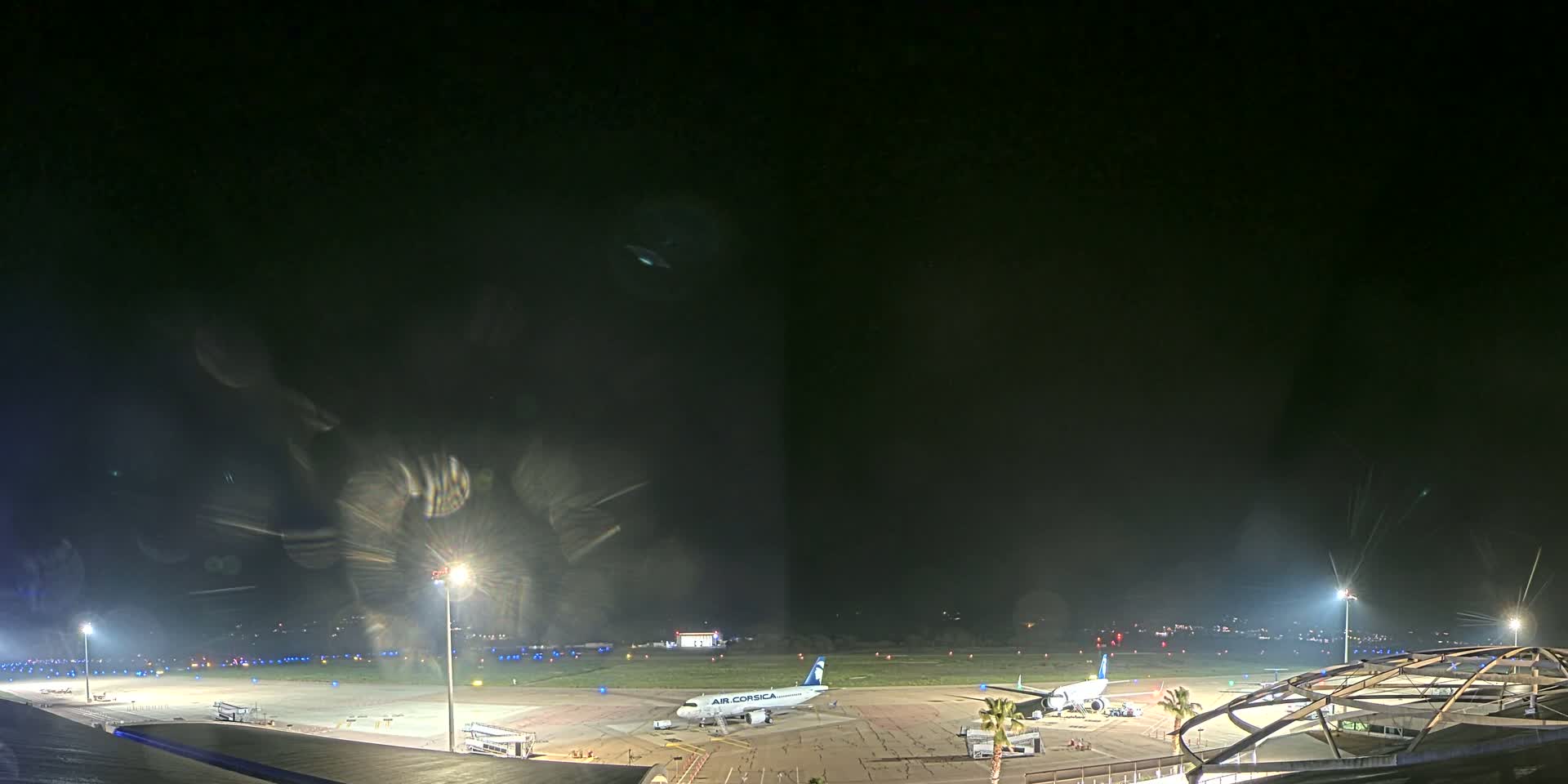 At night, a passenger airplane is parked on an airport tarmac illuminated by bright lights under a dark, clear sky.