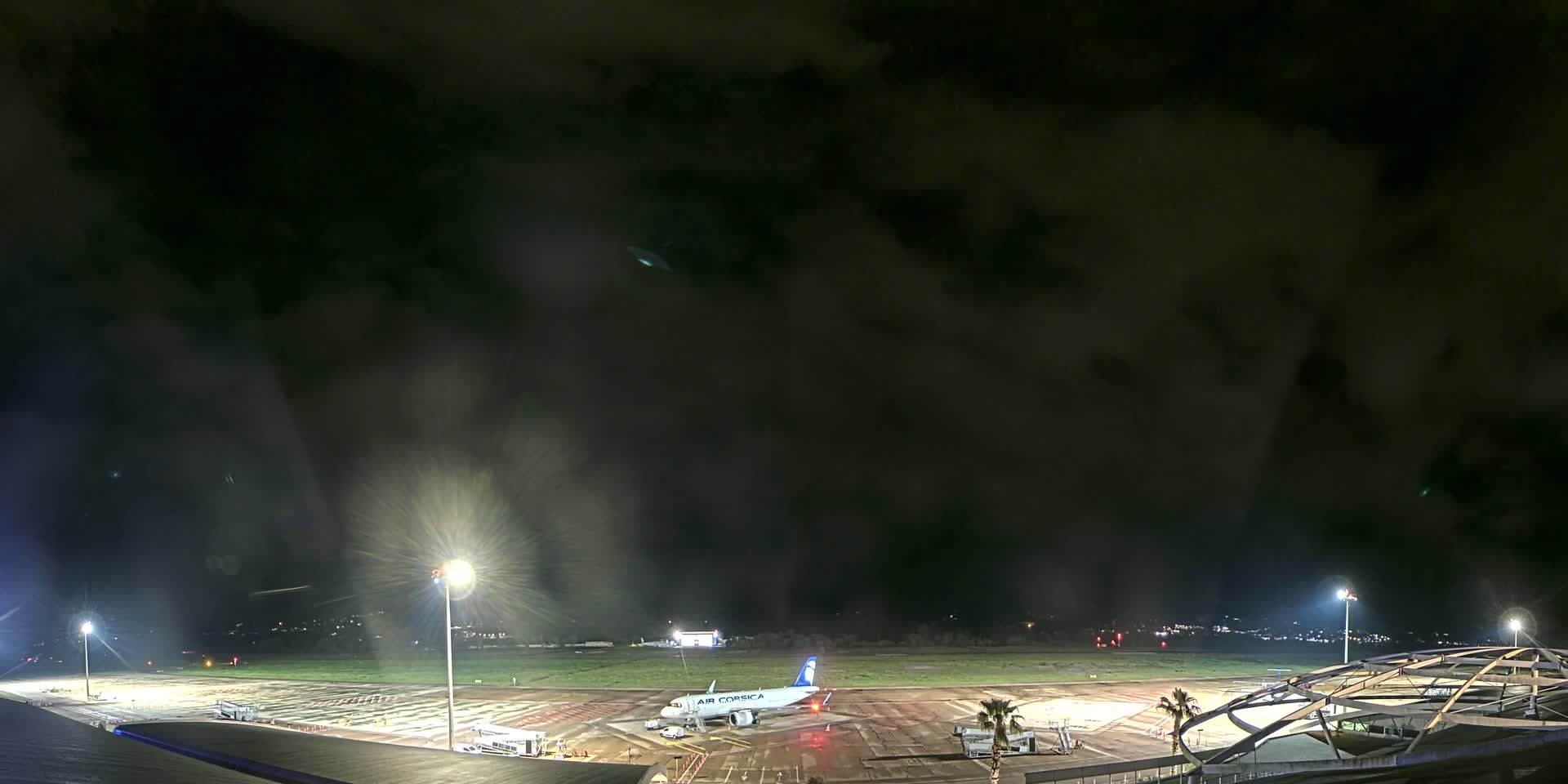 An airplane sits on a tarmac at night under a dark, cloudy sky.