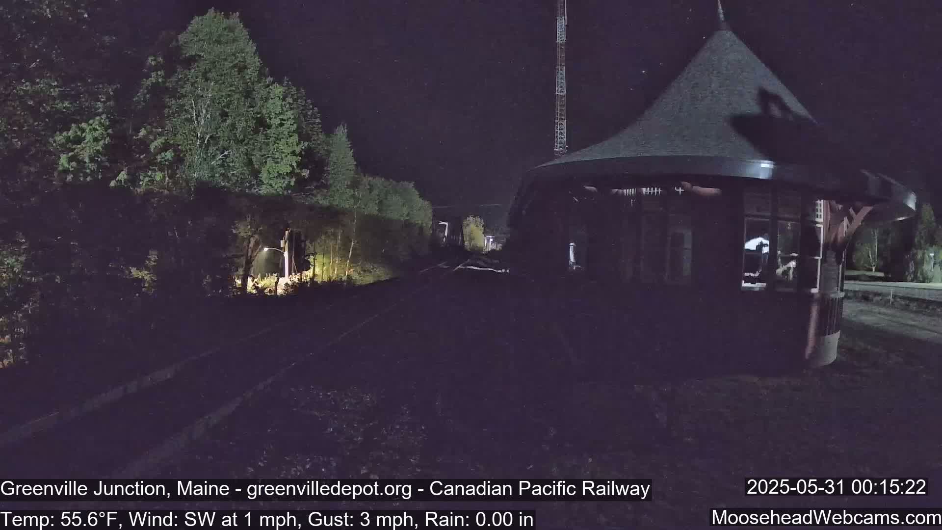 A dark nighttime scene shows a railway track leading to a small, dark gazebo under a mostly clear sky with a light southwest wind.