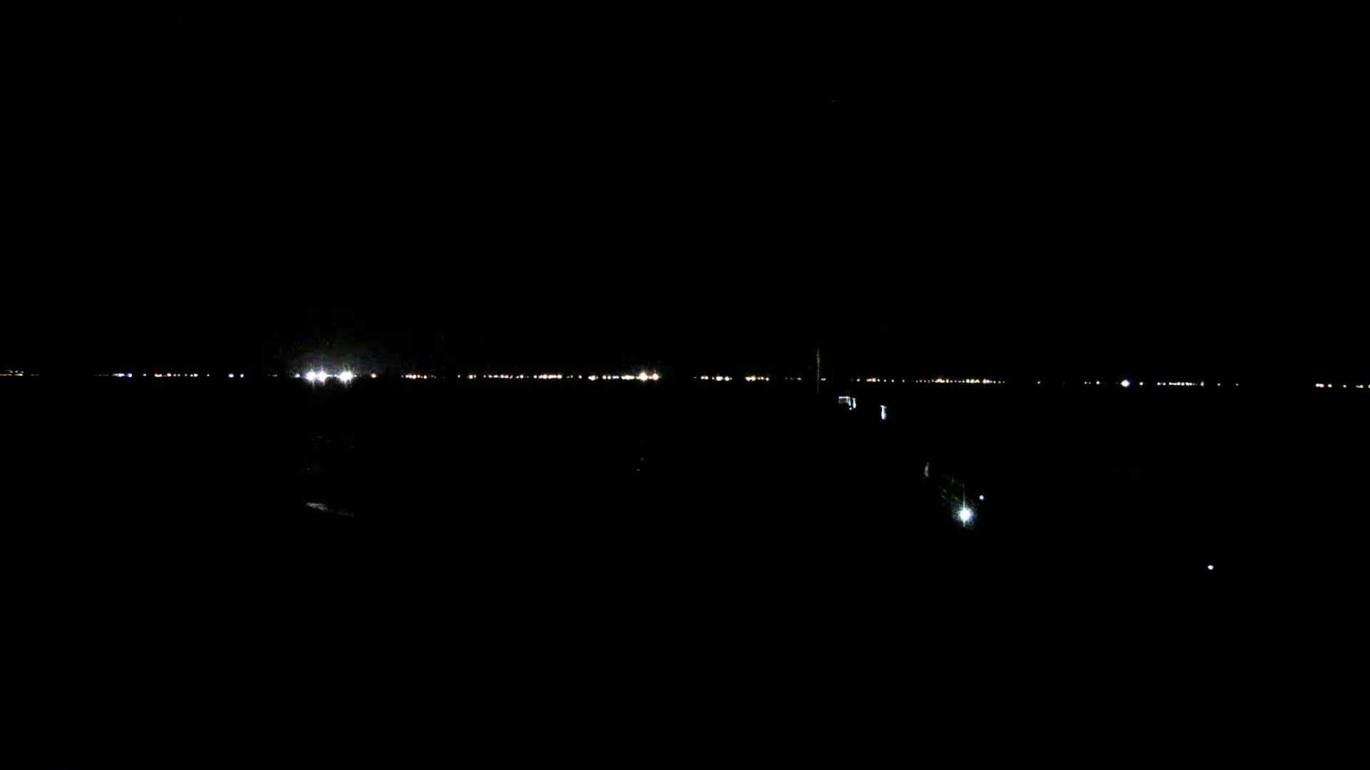 A distant line of lights is visible on a dark, nighttime horizon.