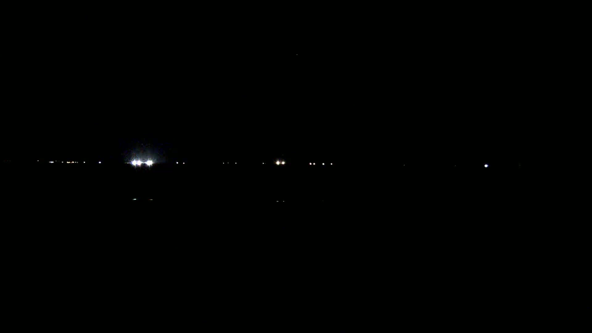 Faint lights from distant vehicles and structures are visible in the dark of night.