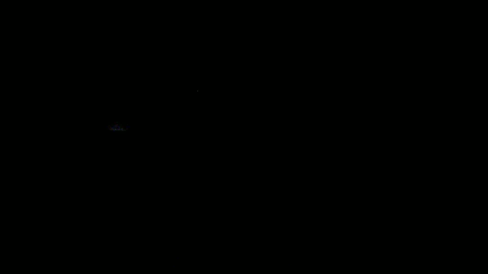 A faint, blurry light source is visible in the otherwise completely dark image.