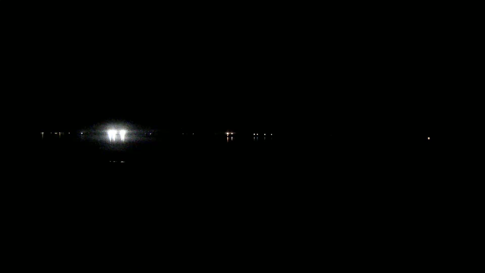 At night, a body of water reflects the faint lights from a distant shoreline.