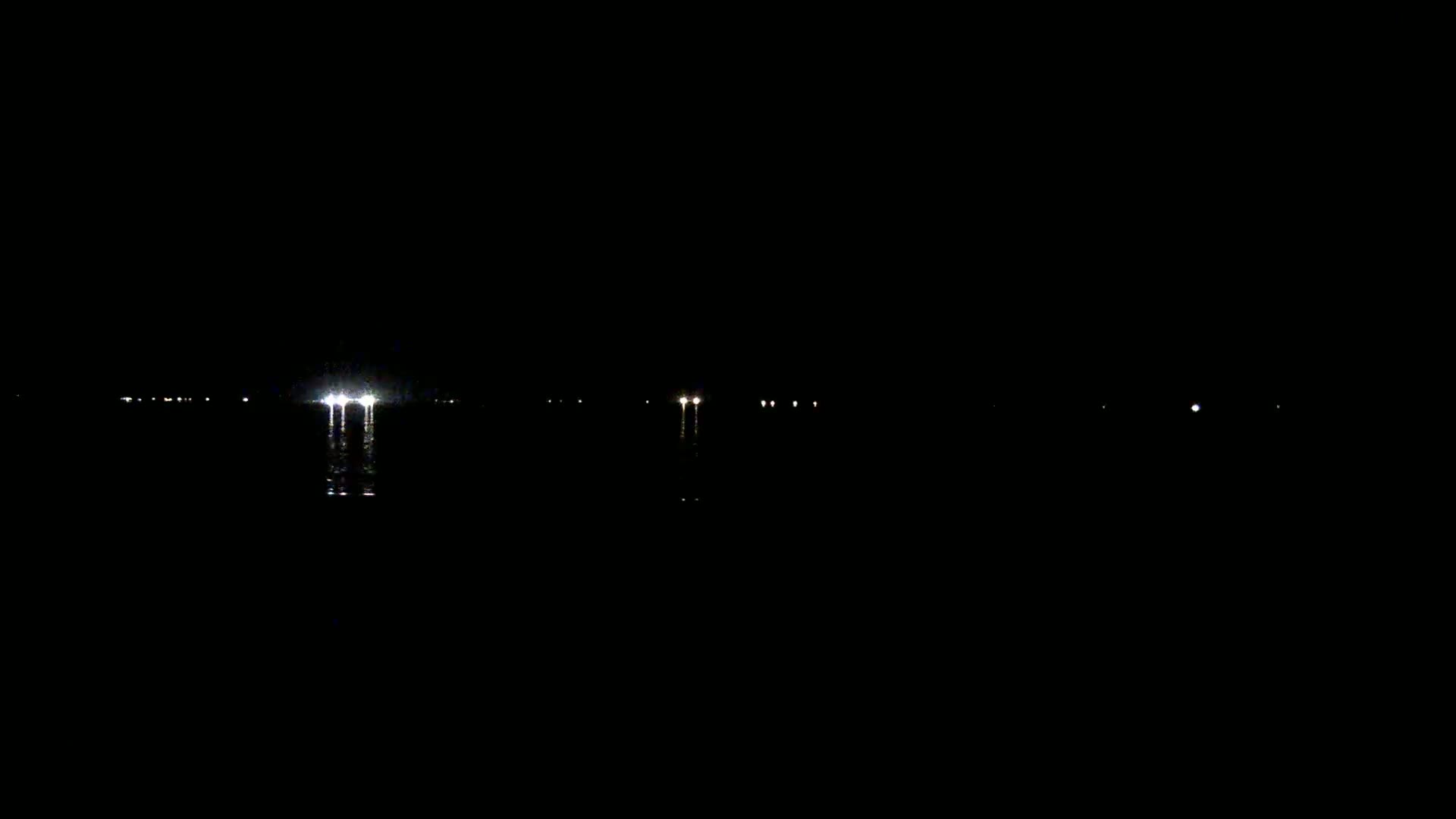 Several distant lights are visible on a dark body of water at night.