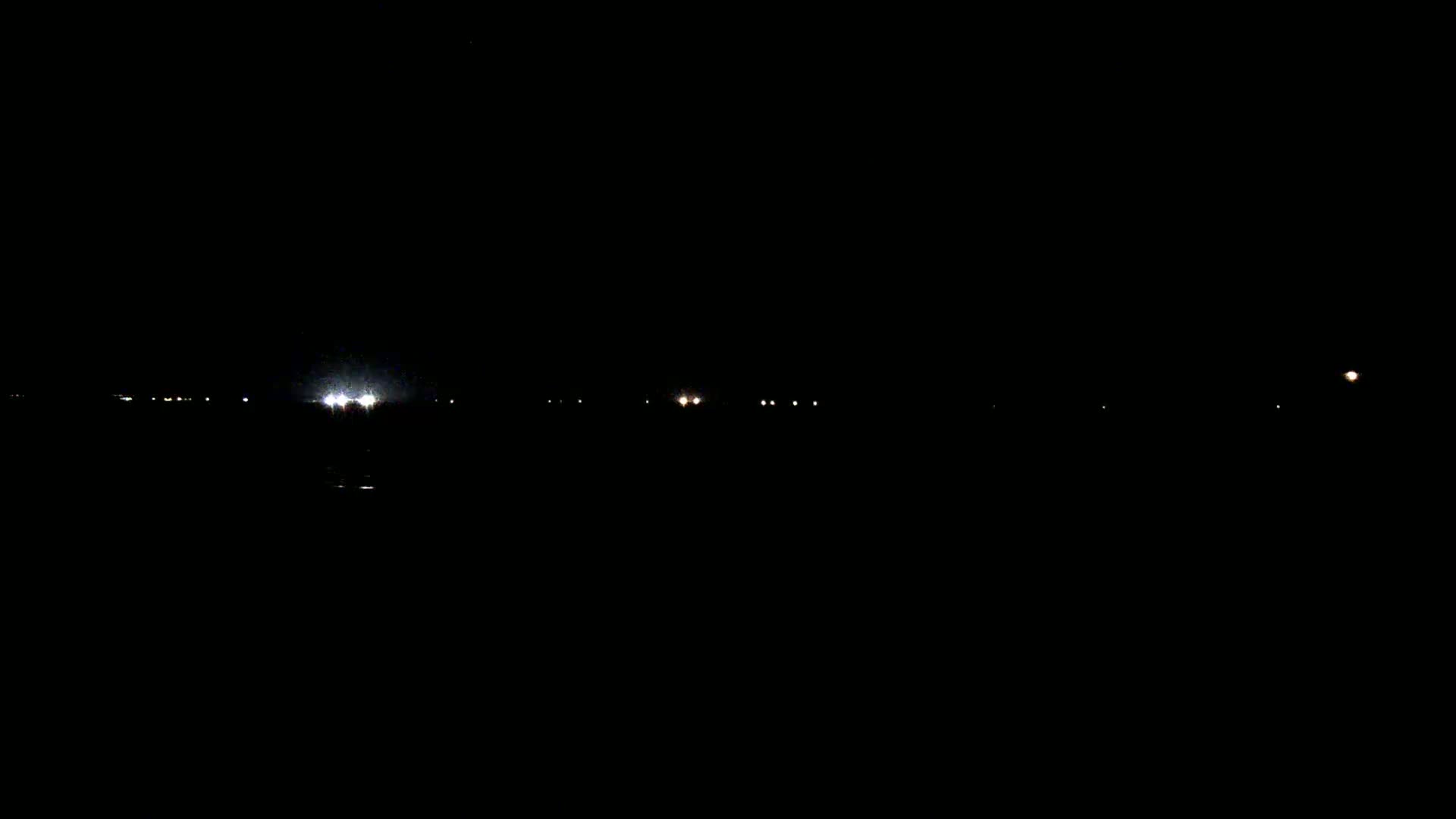A dark, nighttime scene shows several faint lights in the distance on the horizon.