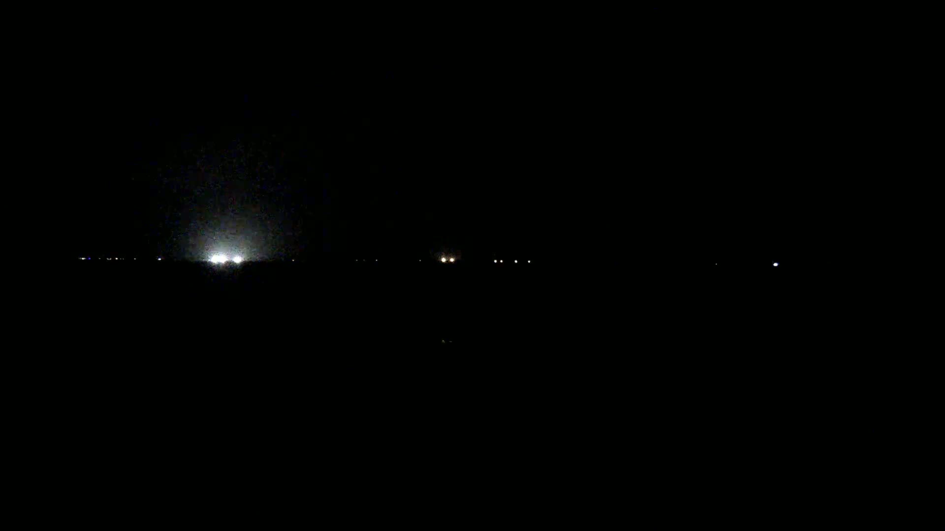 Several faint lights are visible in the distance on a dark, nighttime landscape.