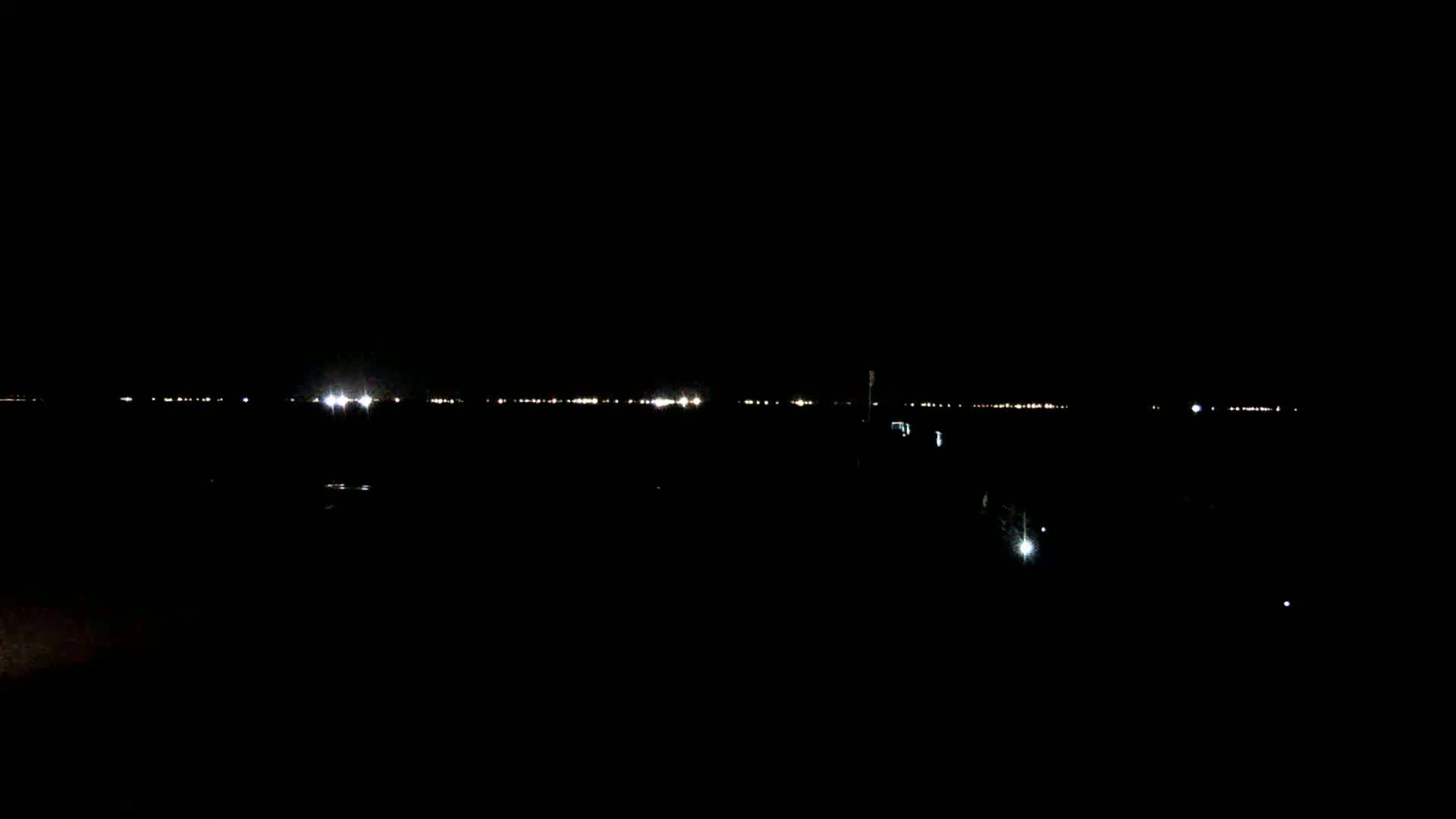A distant line of lights is visible on a dark, nighttime horizon.