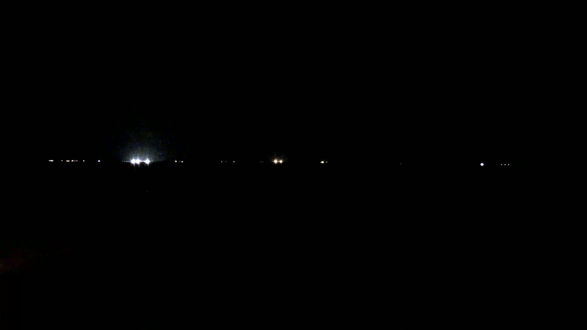 Faint lights from a distant cityscape are visible in the dark night.