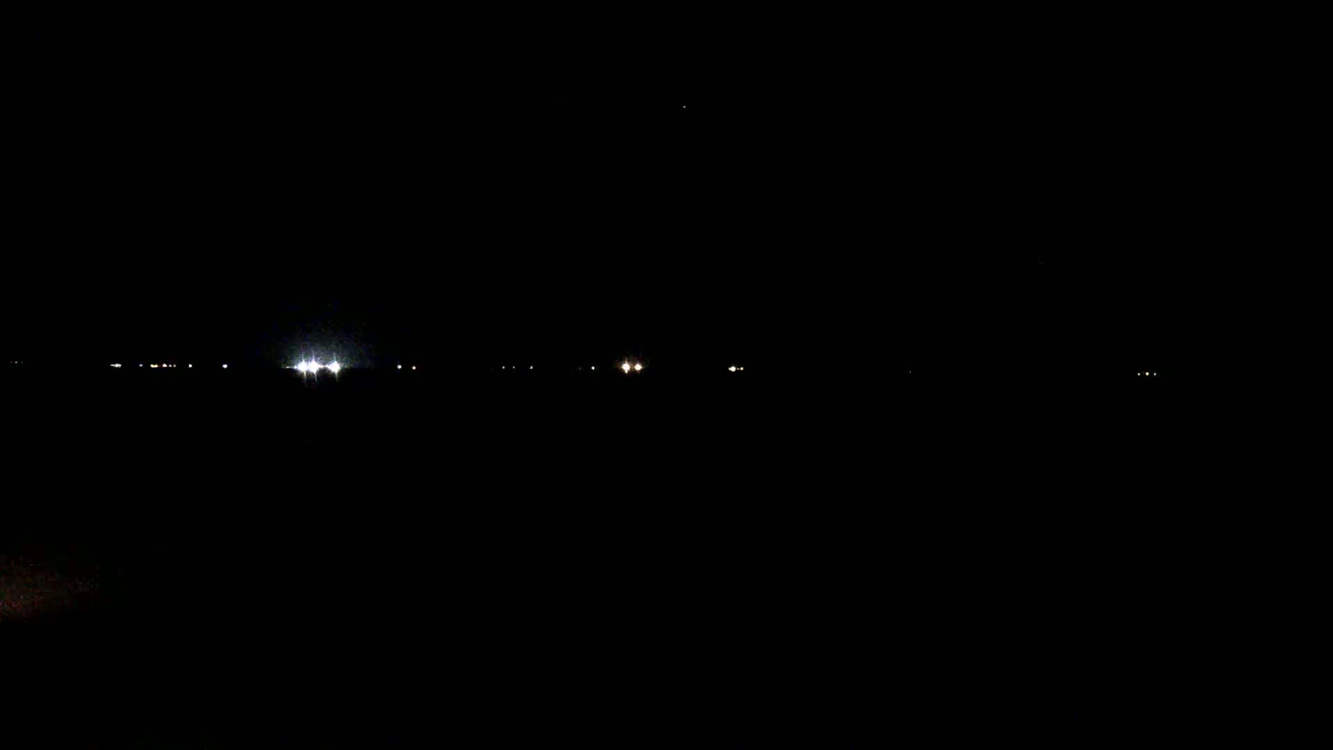 Distant lights are visible on a dark, nighttime landscape.