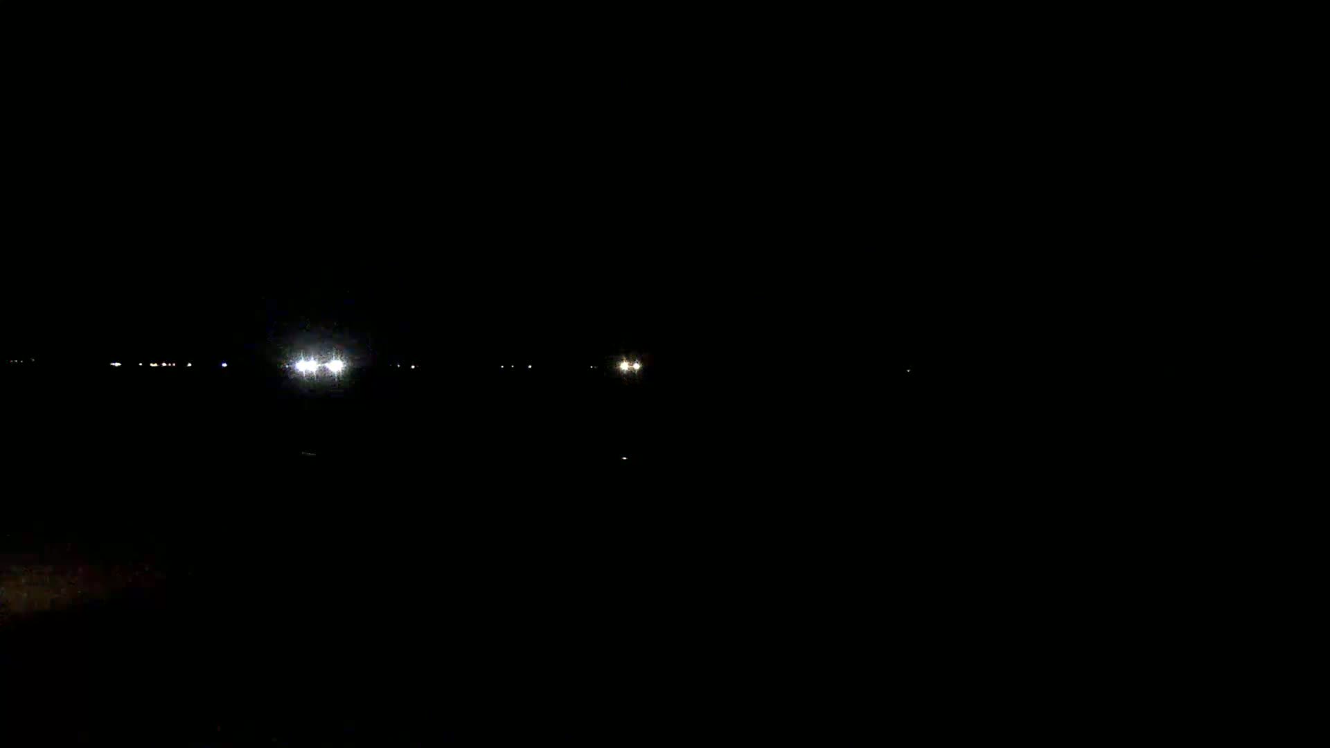 At night, several small, distant lights are visible against a completely dark background.