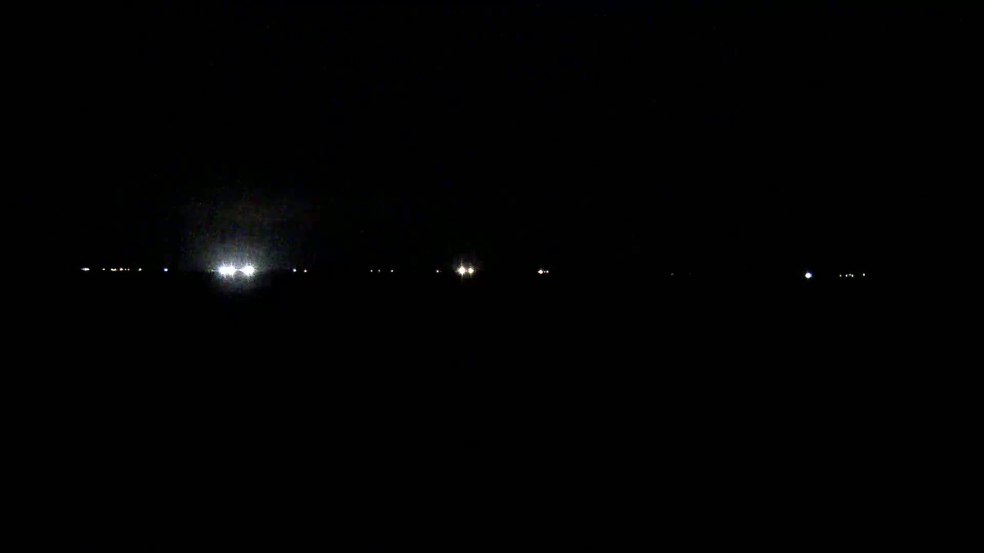 At night, several faint lights are visible in the distance across a dark landscape.