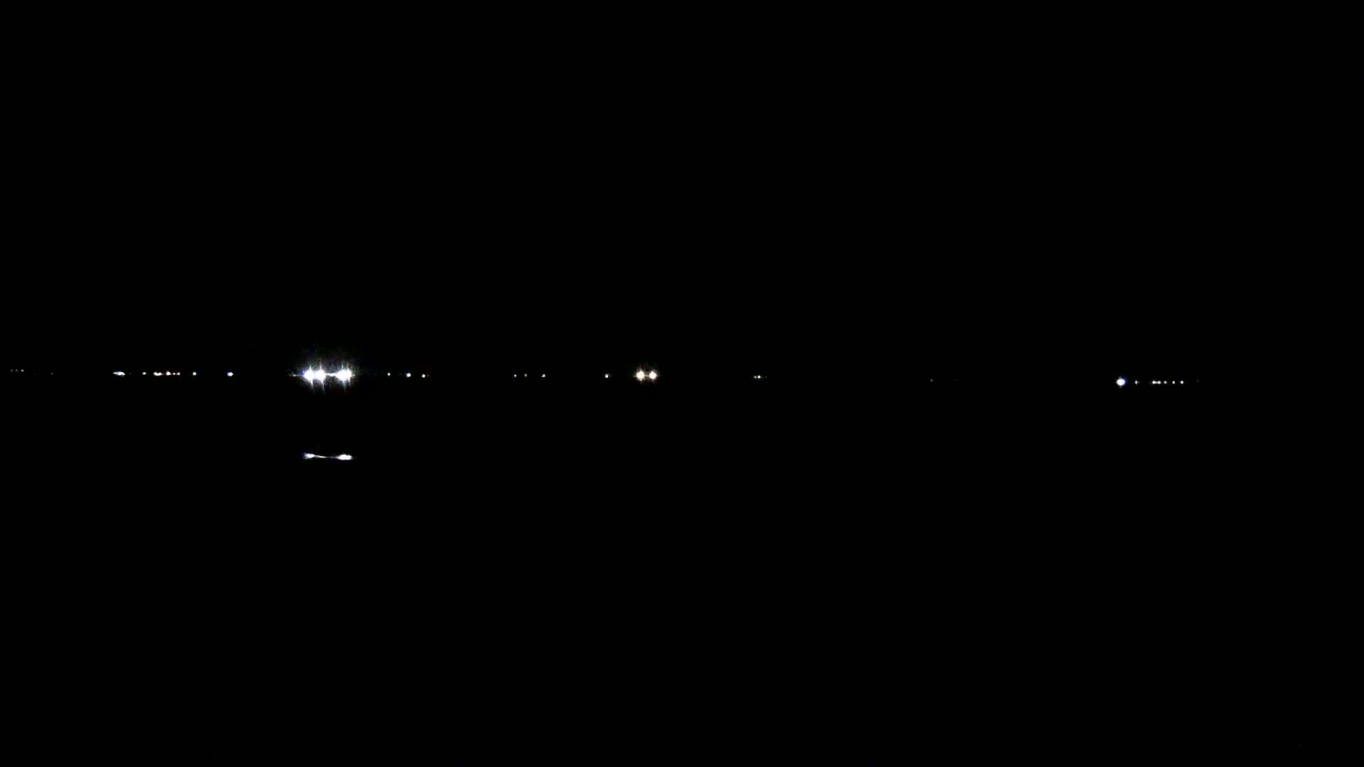 Faint, distant lights are visible at night across a dark, still body of water.