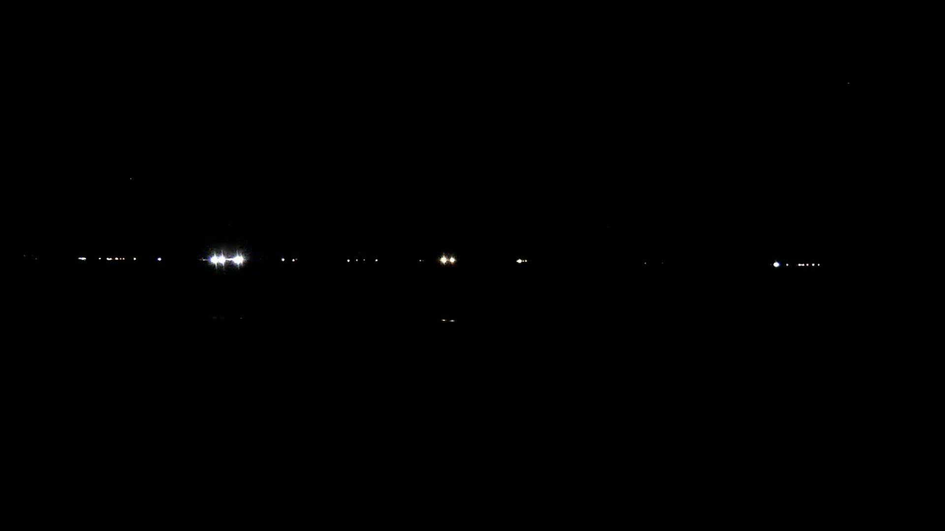 Distant lights are visible across a dark, nighttime landscape.