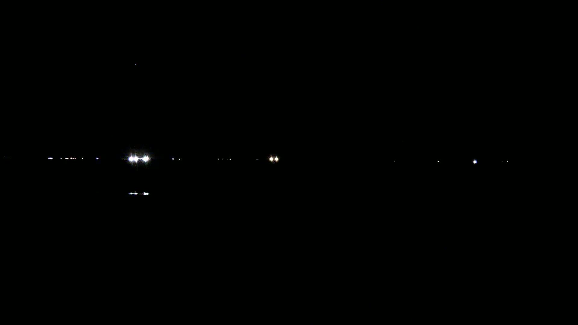Distant lights are visible across a dark, still body of water at night.