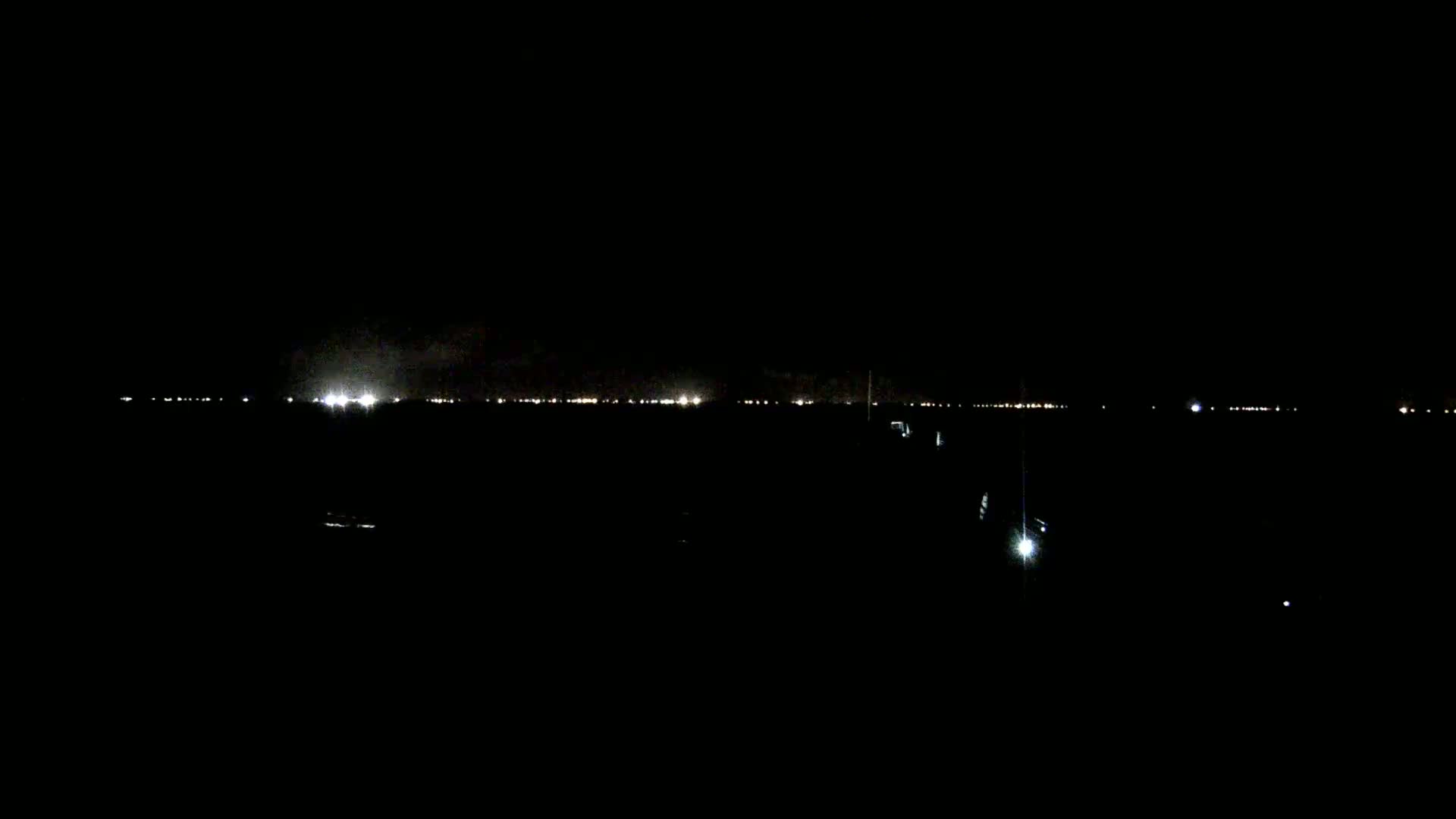 A nighttime view of a distant city skyline illuminated by faint lights under a dark sky.