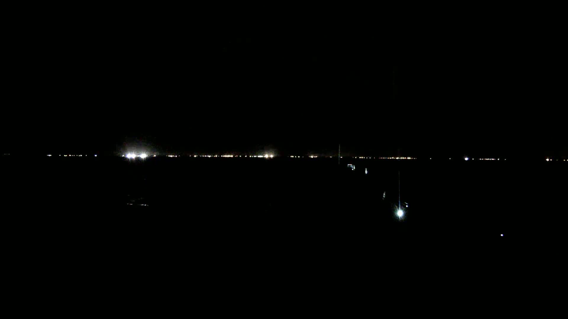 A dark, nighttime scene shows a distant line of lights on the horizon.