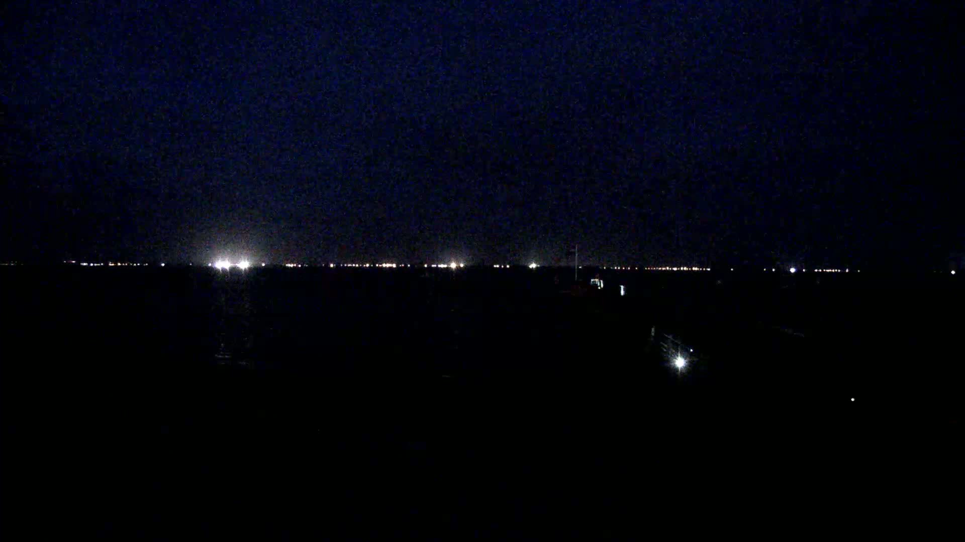 A dark, nighttime scene shows a distant line of lights on the horizon.