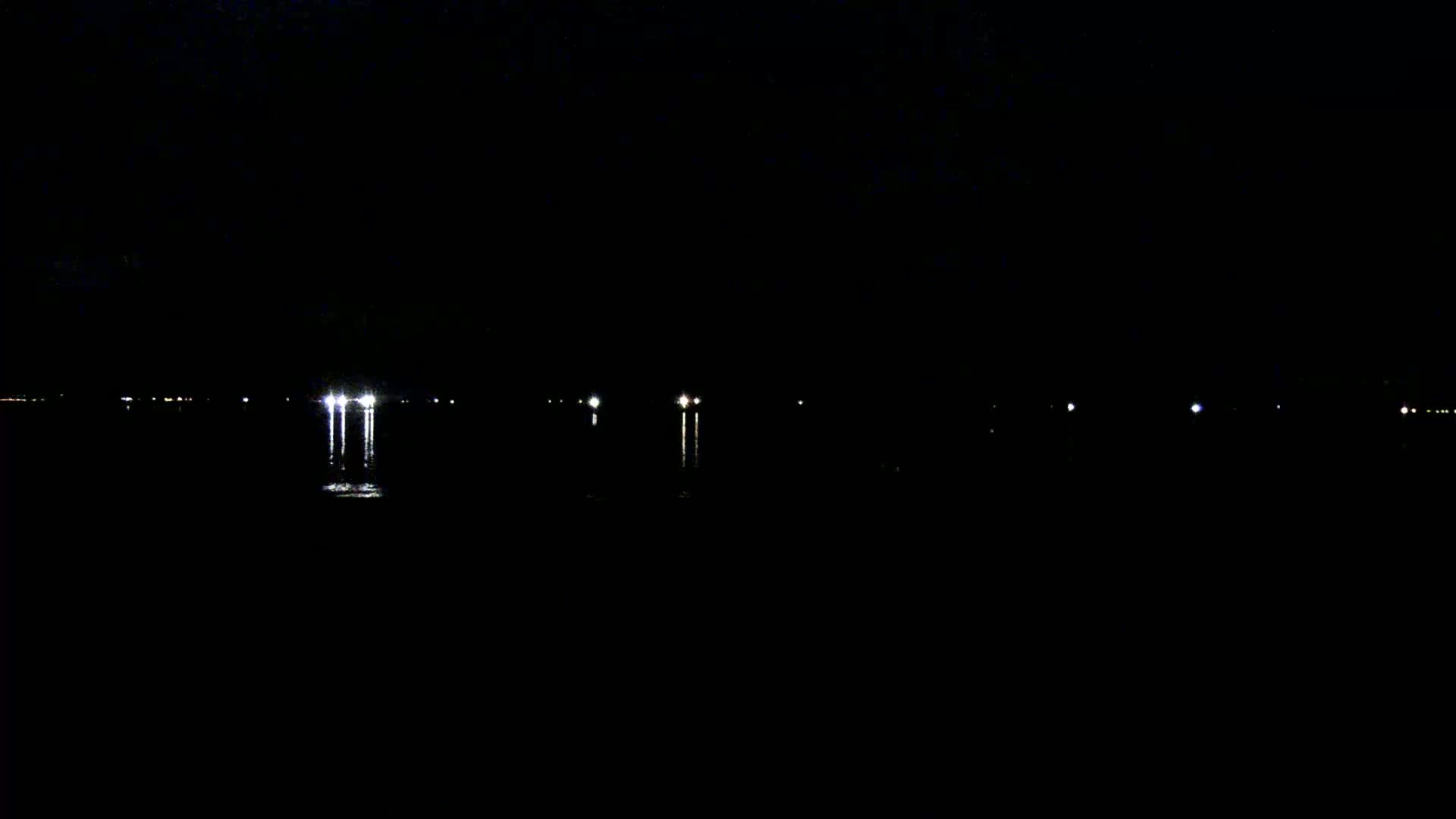 At night, several faint lights are visible across a dark body of water.