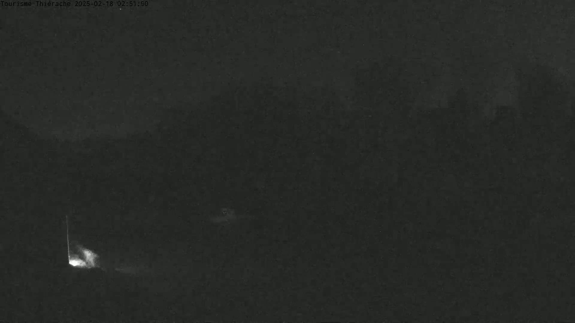 A dark, nighttime outdoor scene shows a faint light source in the lower left corner.