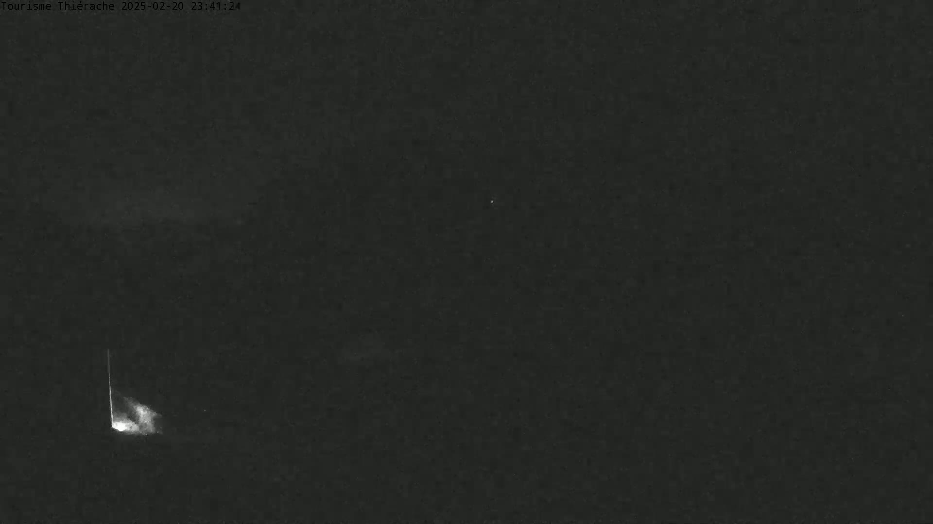 A bright streak of light, possibly a meteor, is visible in the night sky.