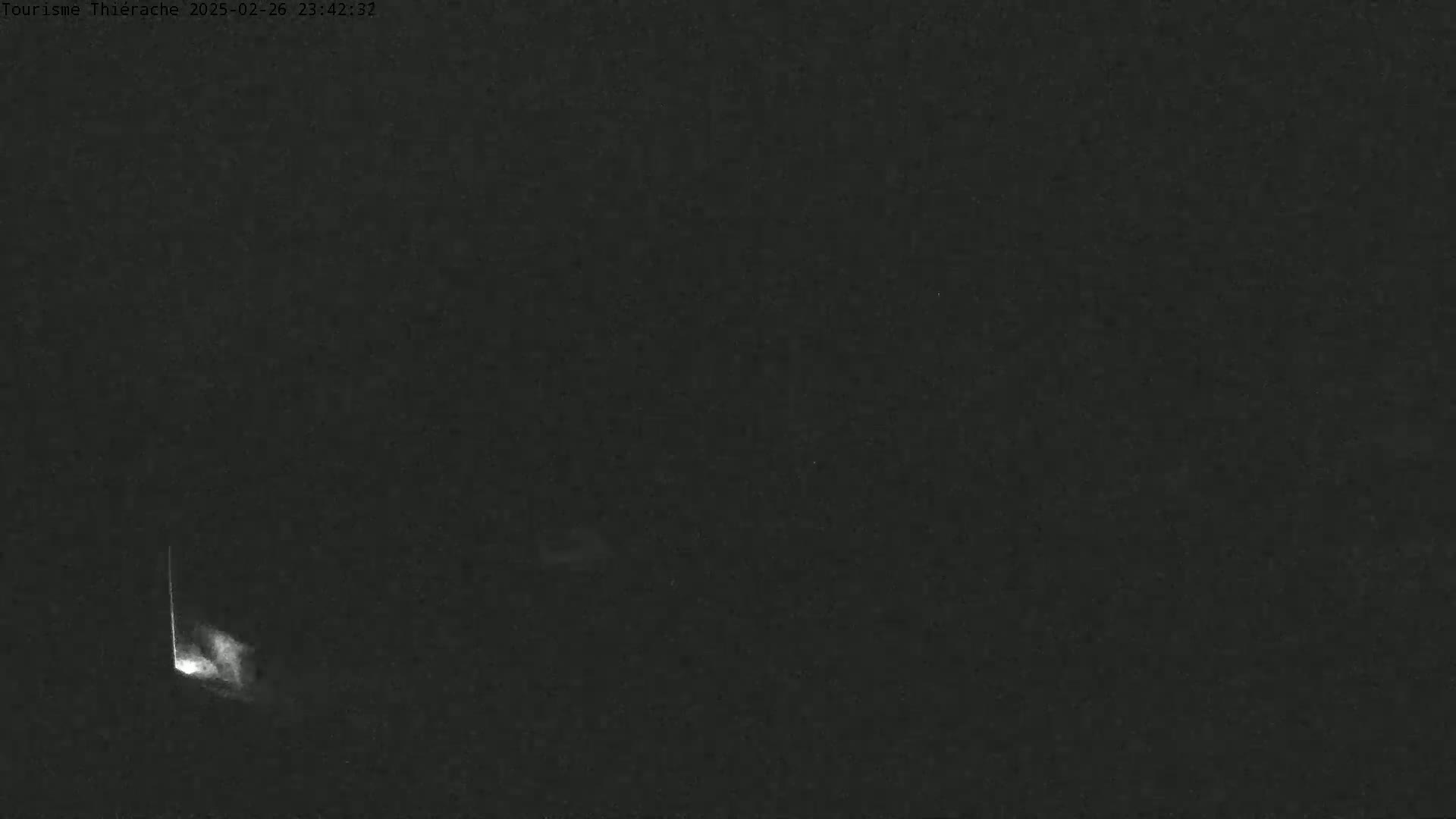 A bright, vertical streak of light appears in the lower left of a dark, nighttime outdoor scene.