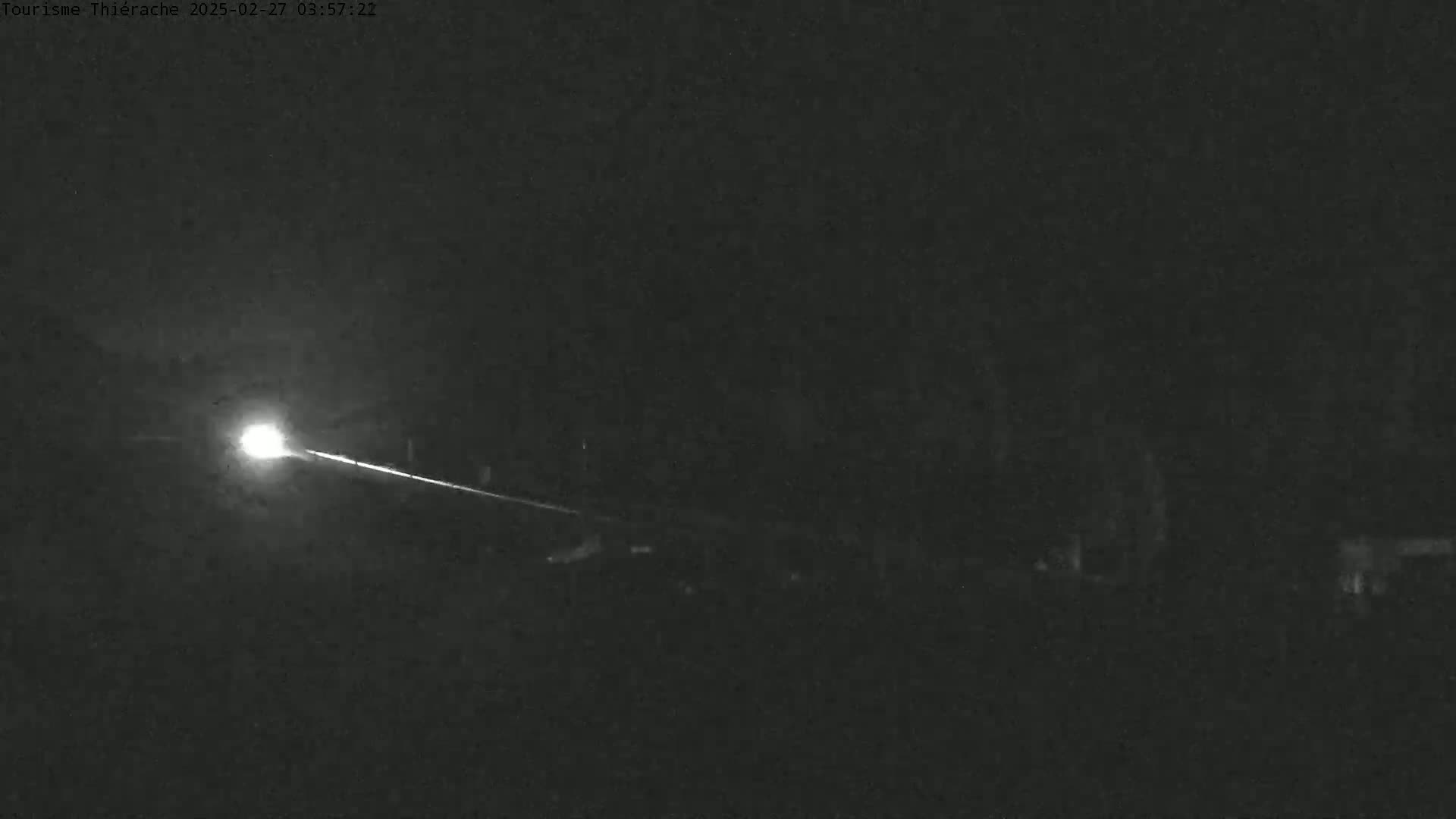 A bright light streaks across a dark, nighttime landscape.