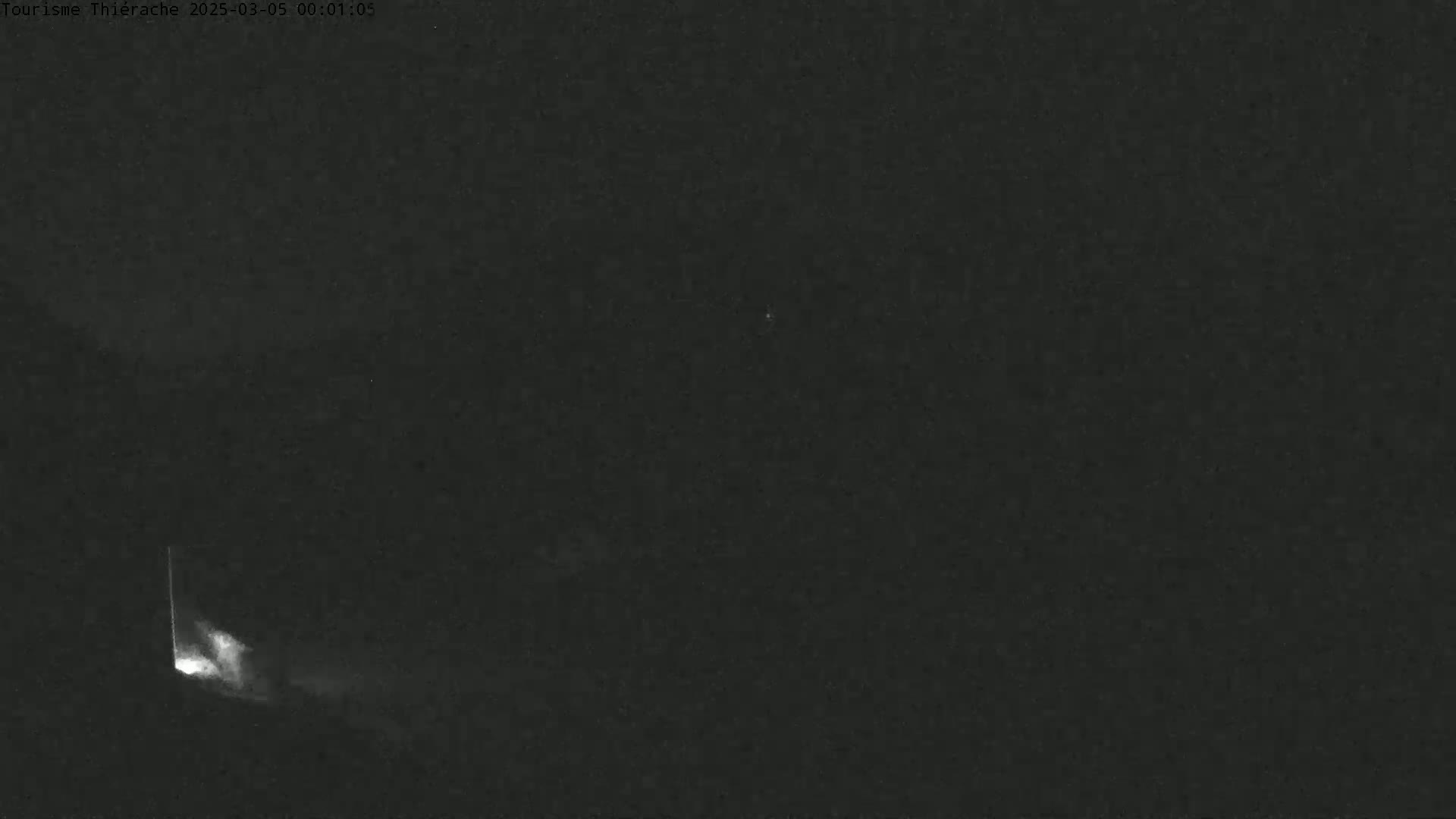 A nighttime, dark scene shows a faint, bright light emanating from the lower left corner.