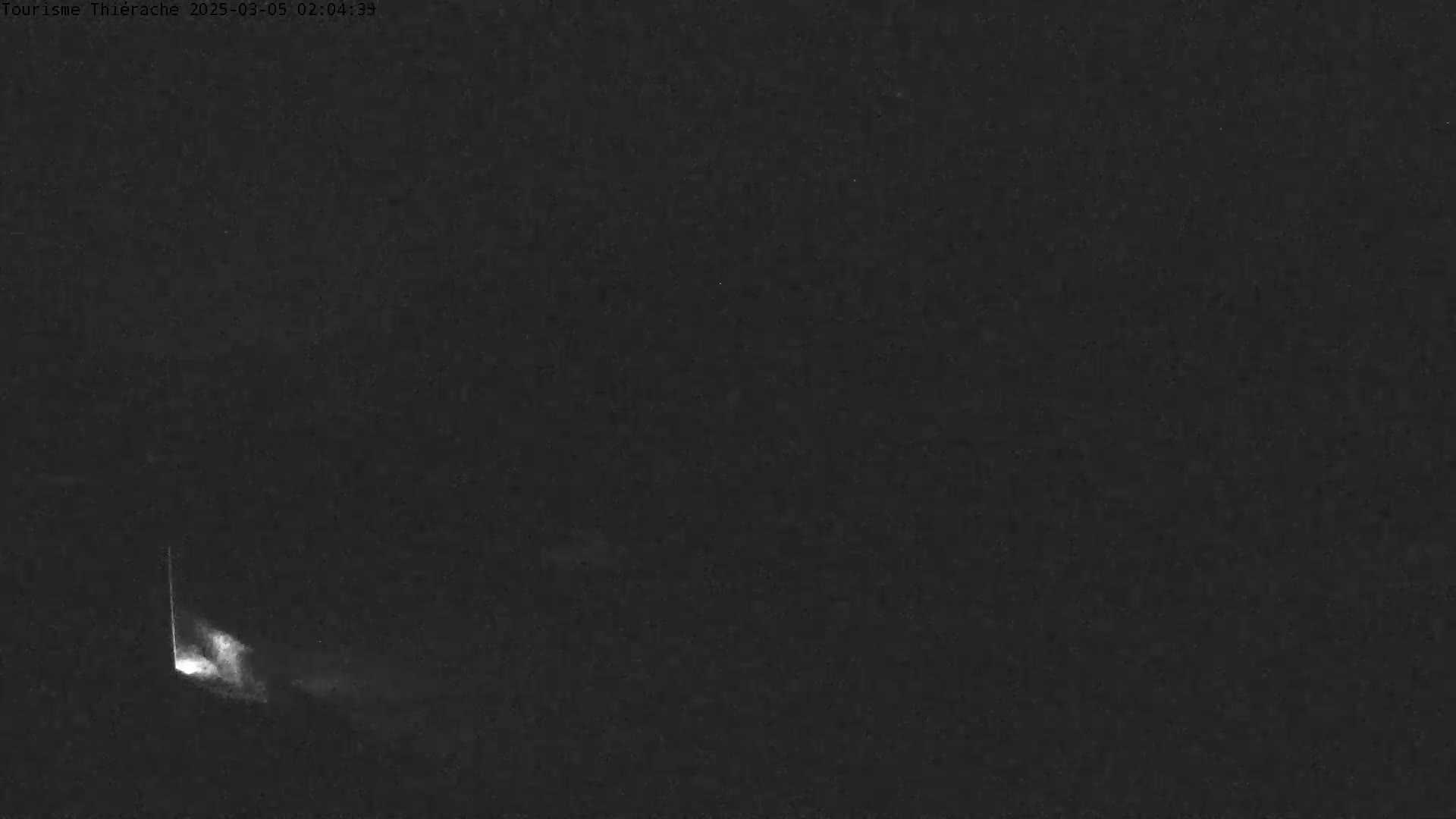 A bright light emanates from a point near the bottom left corner of a dark, nighttime scene.
