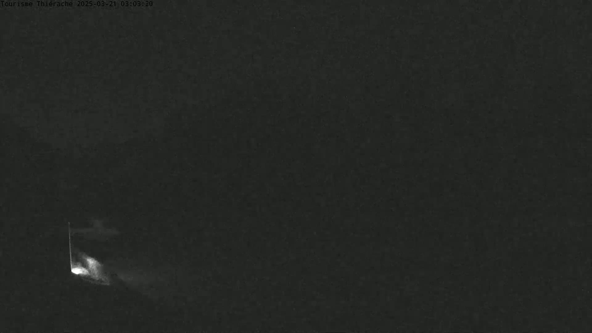 A low-light image shows a faint light emanating from what appears to be a structure at night.