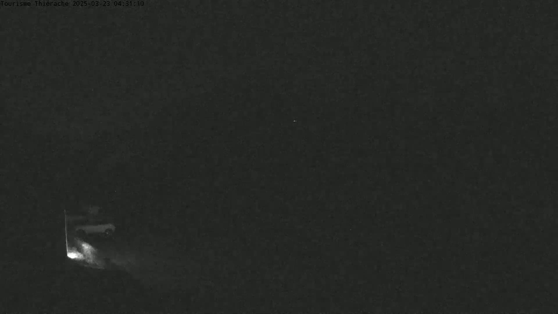 A vehicle's headlights illuminate a dark, nighttime scene as it exits a tunnel or dark area.