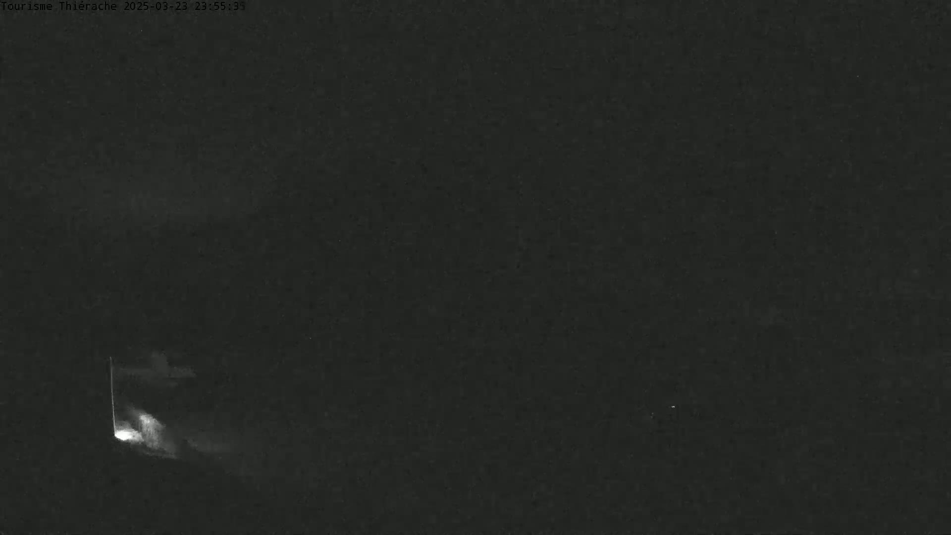 A dimly lit, dark nighttime scene shows a faint, bright light emanating from the lower left corner.