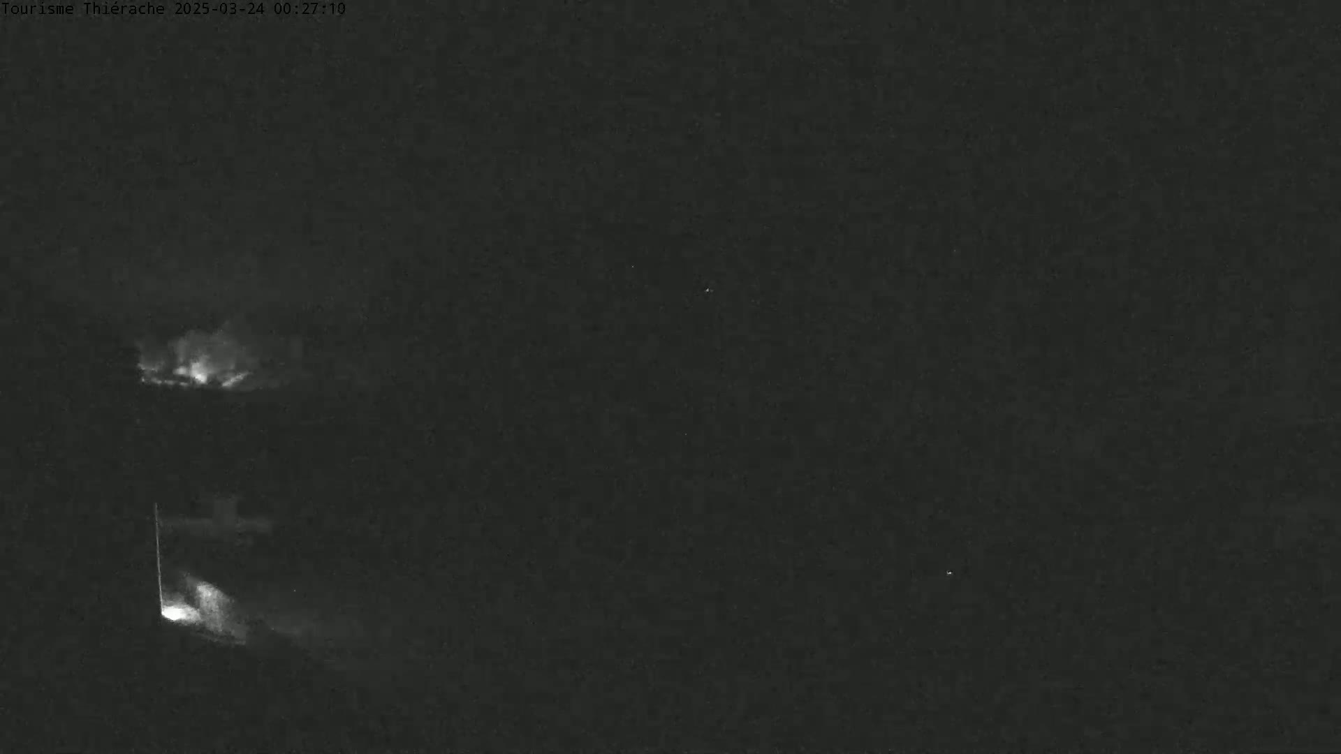 A nighttime, low-light image shows a faint, bright area in the lower left corner and a brighter area higher up and to the left, against a dark, mostly featureless background.