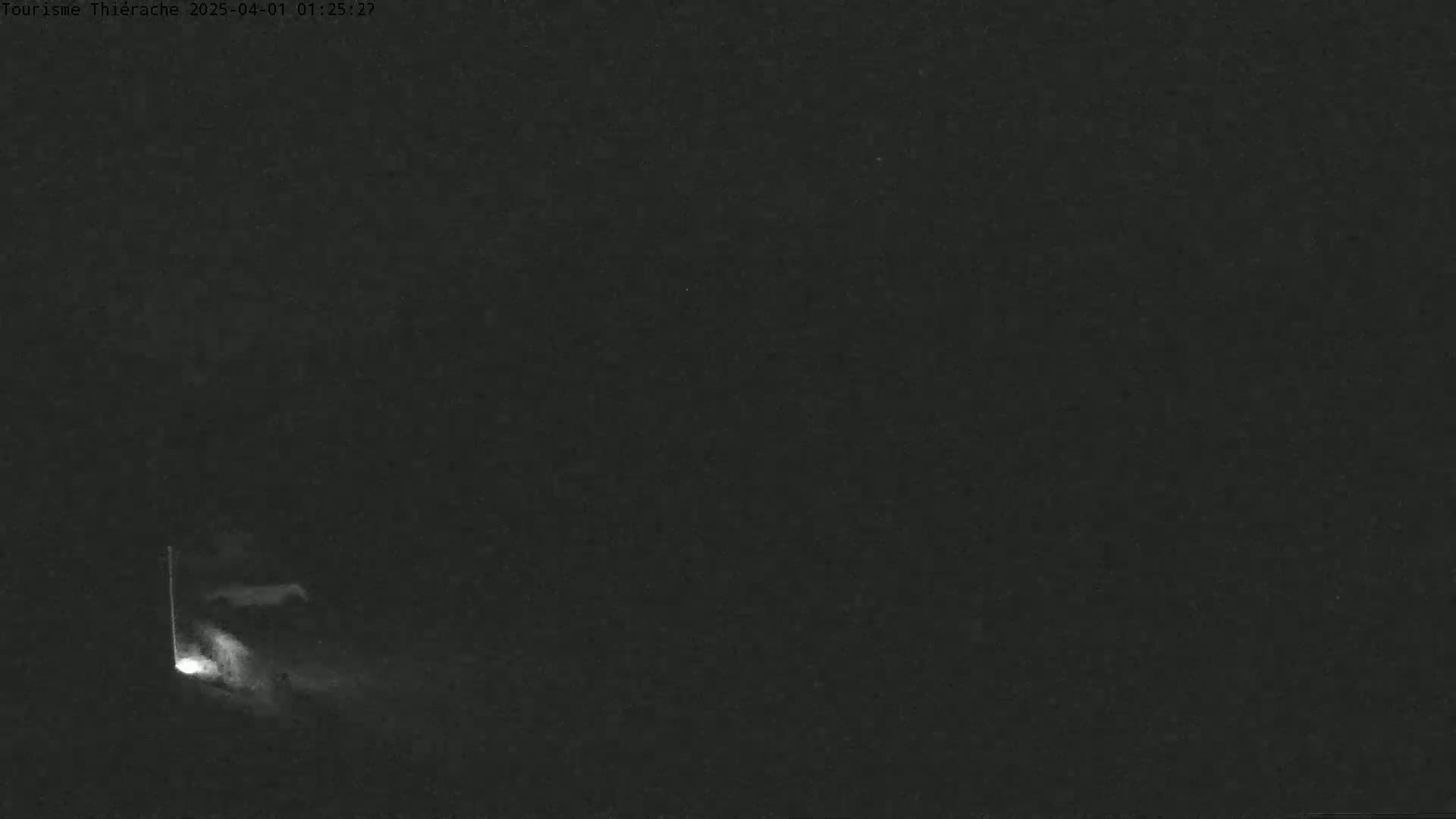A nighttime image shows a dimly lit area with a faint light source near the bottom left corner.