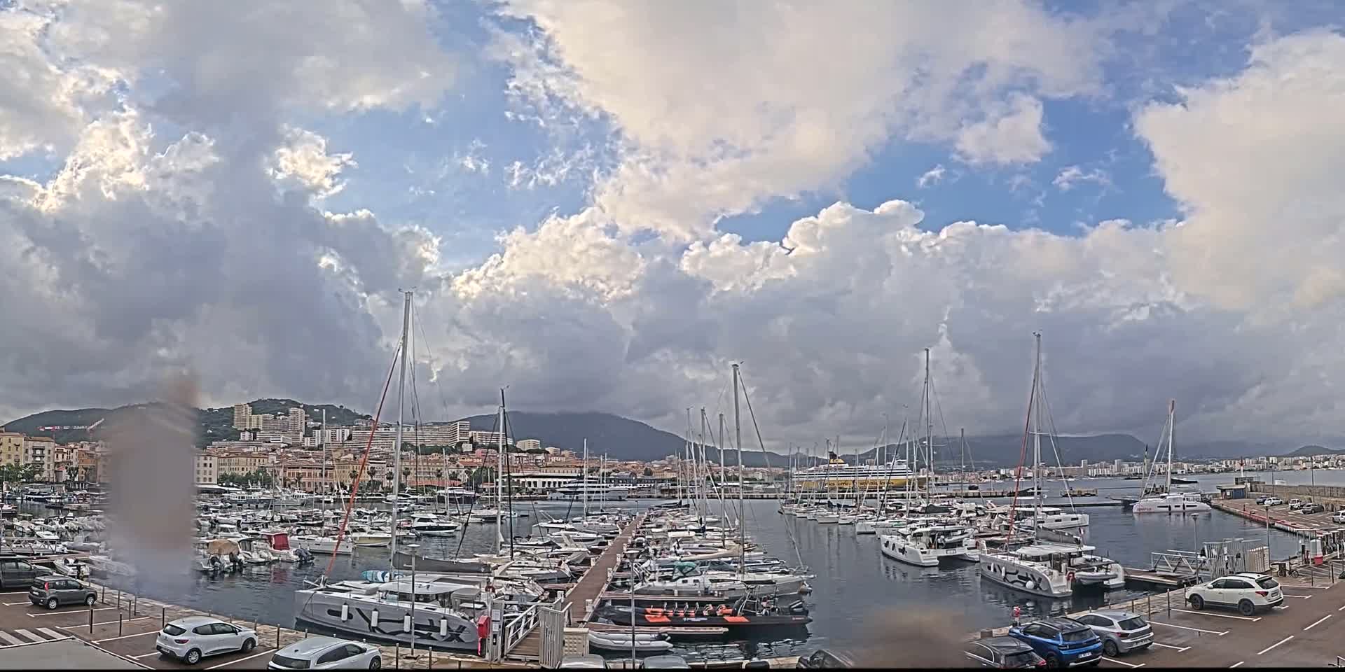 A harbor filled with numerous sailboats and yachts under a partly cloudy sky.