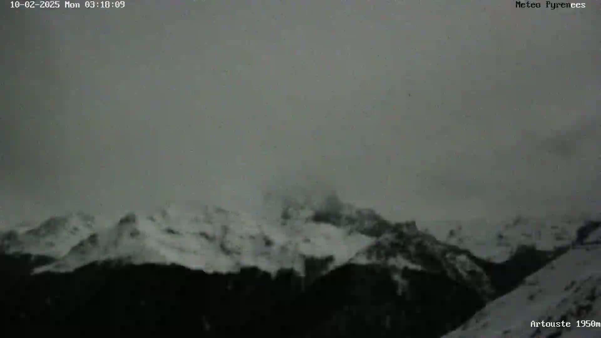 Snow-covered mountains are visible under an overcast sky.