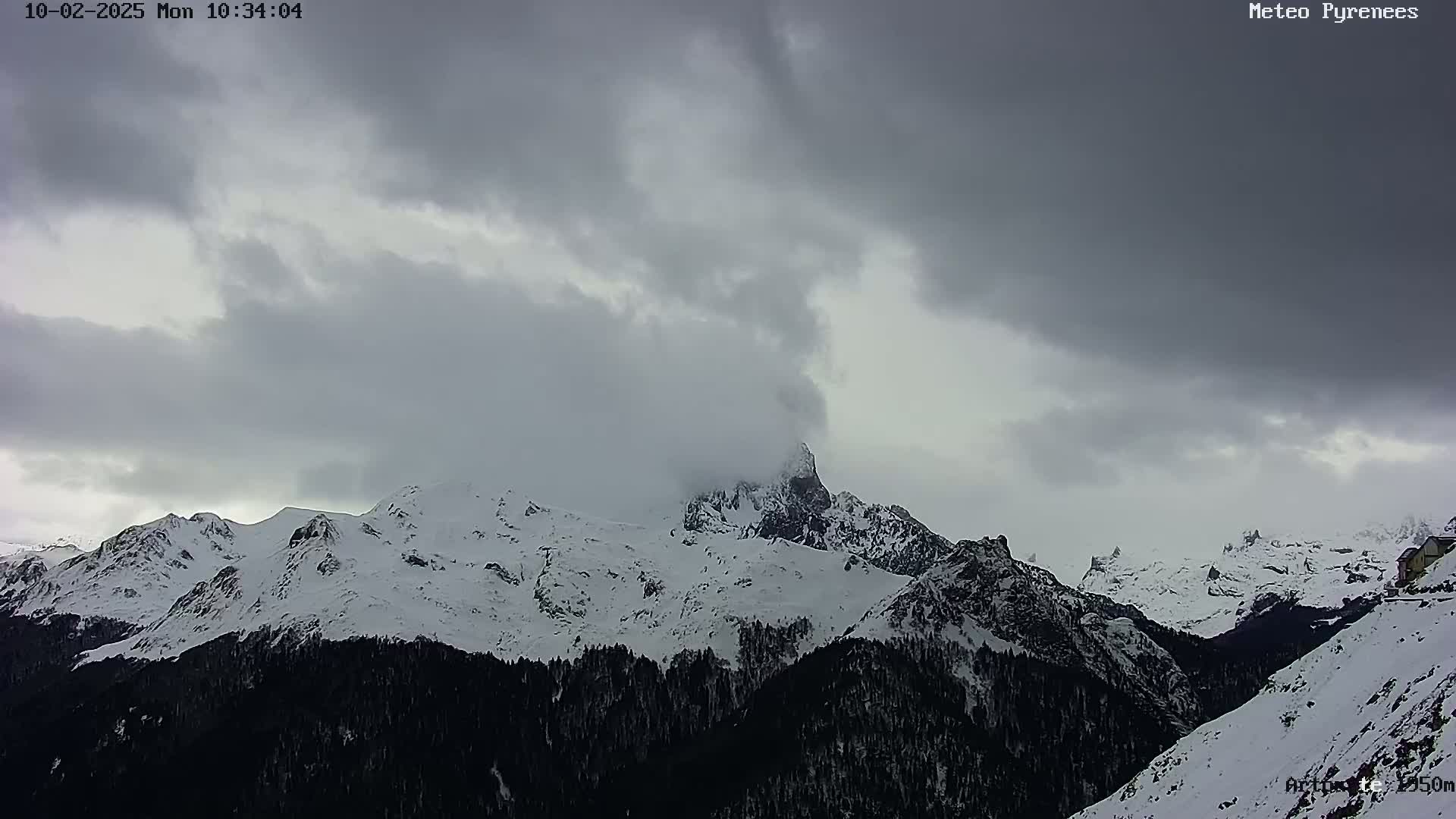 Snow-covered mountains are partially obscured by a heavily overcast sky.