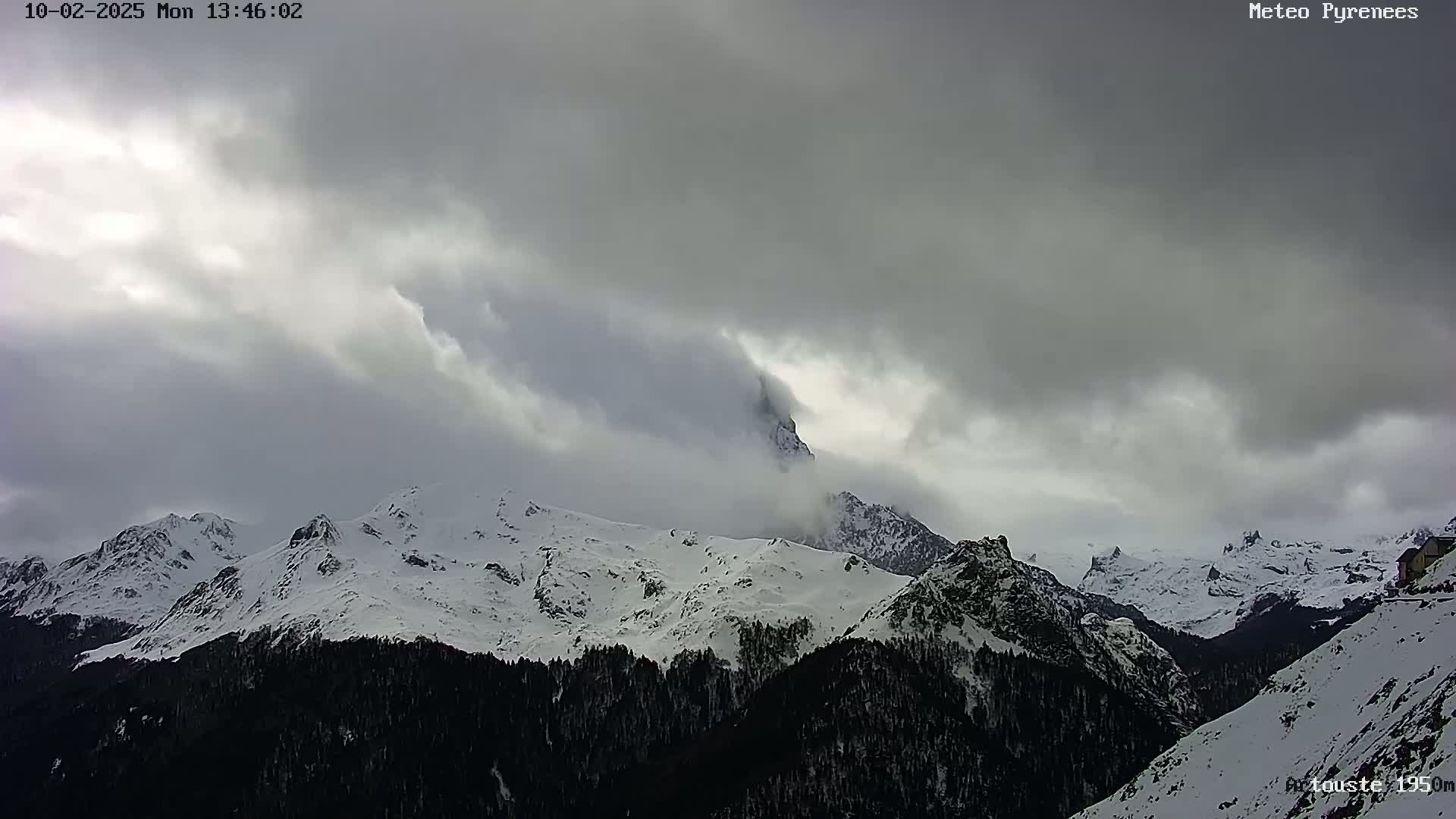 Snow-covered mountains are partially obscured by a cloudy, overcast sky.