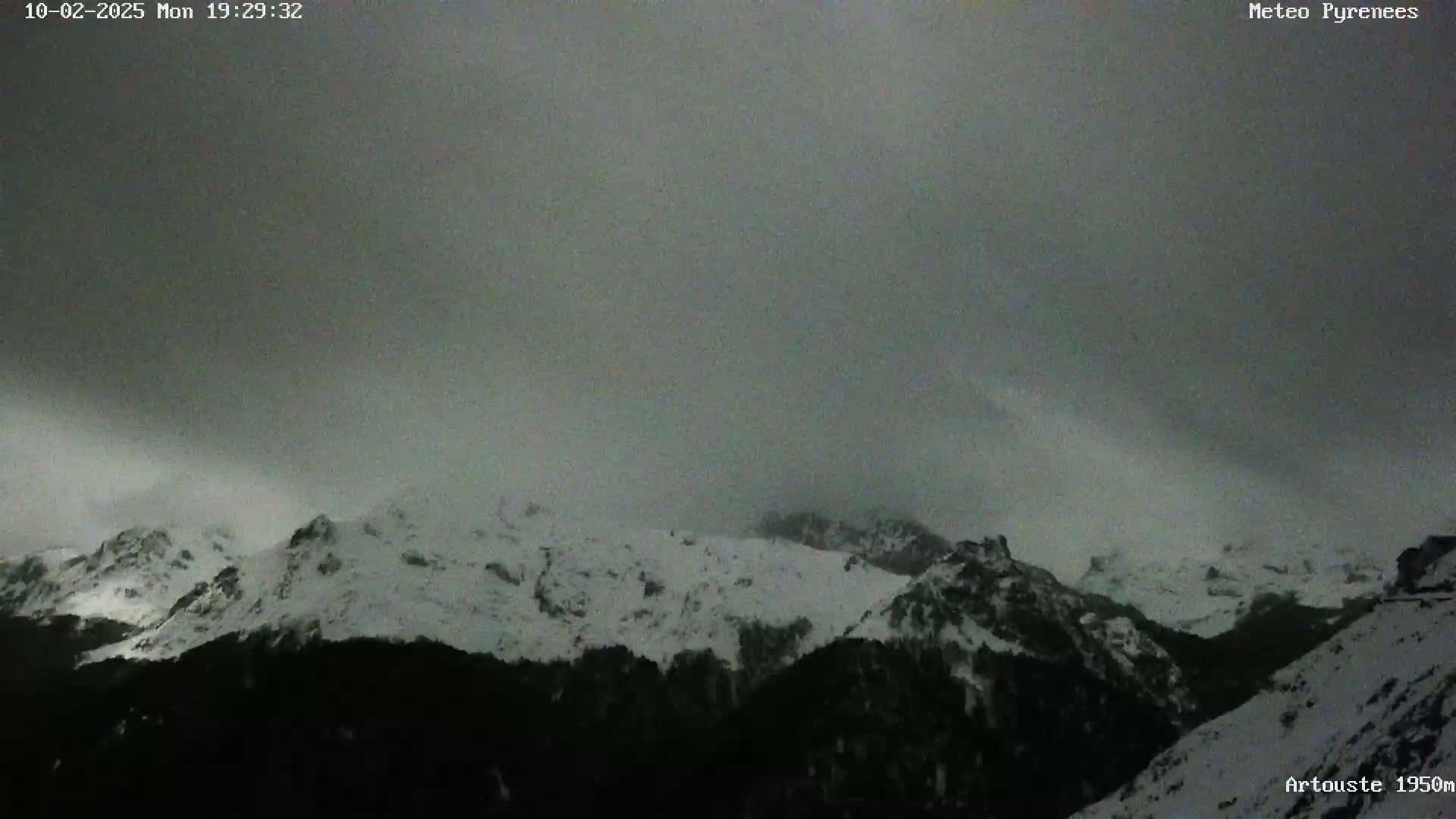 Snow-covered mountains are visible under a dark, overcast sky.