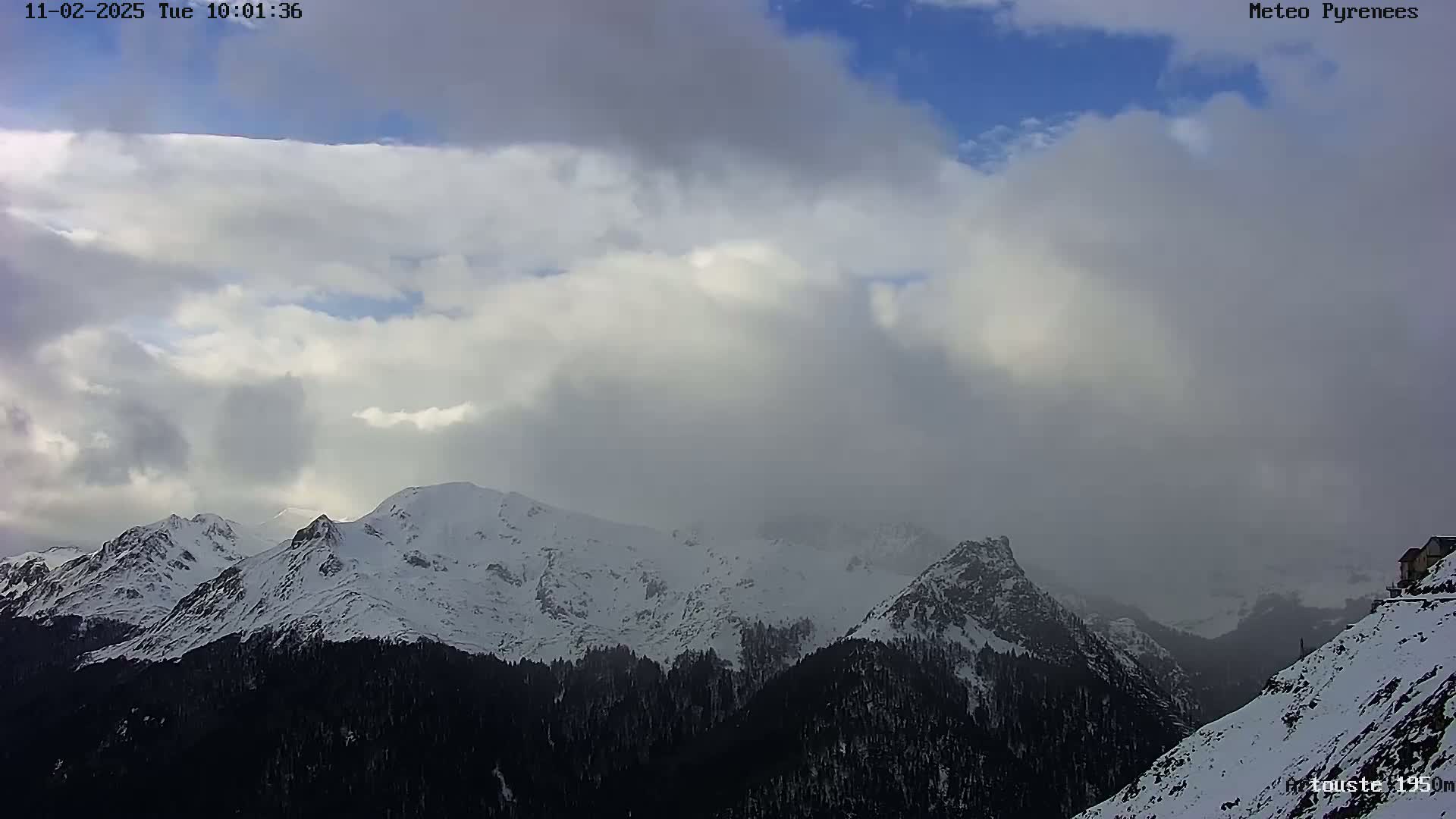 Snow-capped mountains are partially obscured by a cloudy, overcast sky.