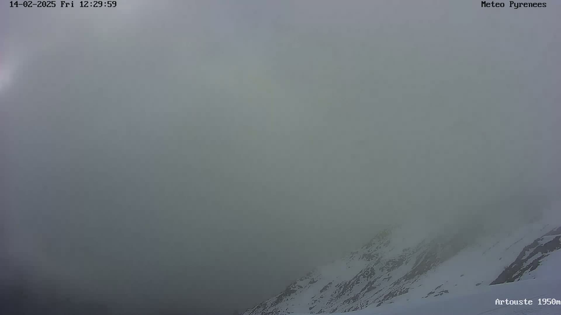 A snow-covered mountain peak is partially obscured by thick fog.