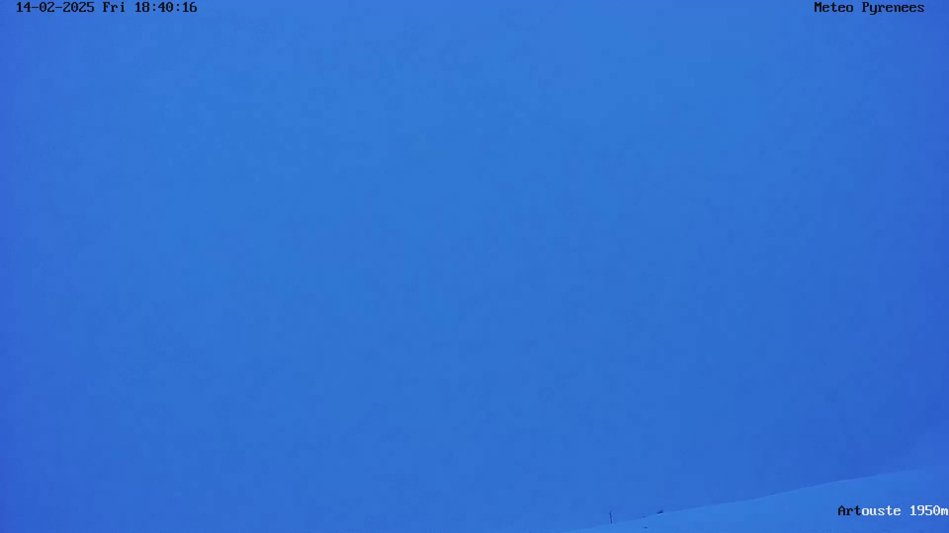 A mostly clear, blue sky over a snow-covered landscape.