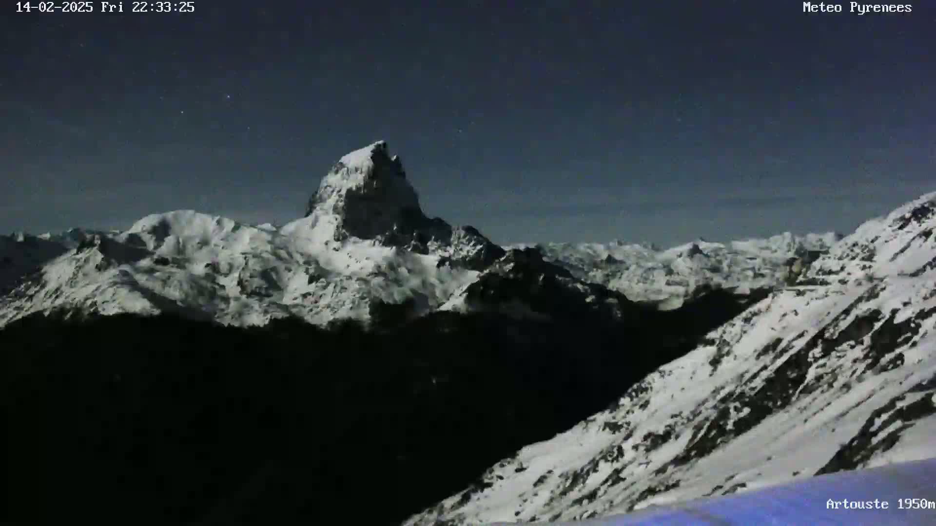 A snow-covered mountain range is visible under a dark, clear night sky.