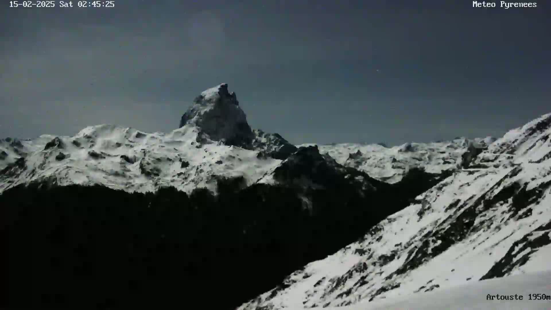 A snow-covered mountain range is visible under a dark, overcast sky.