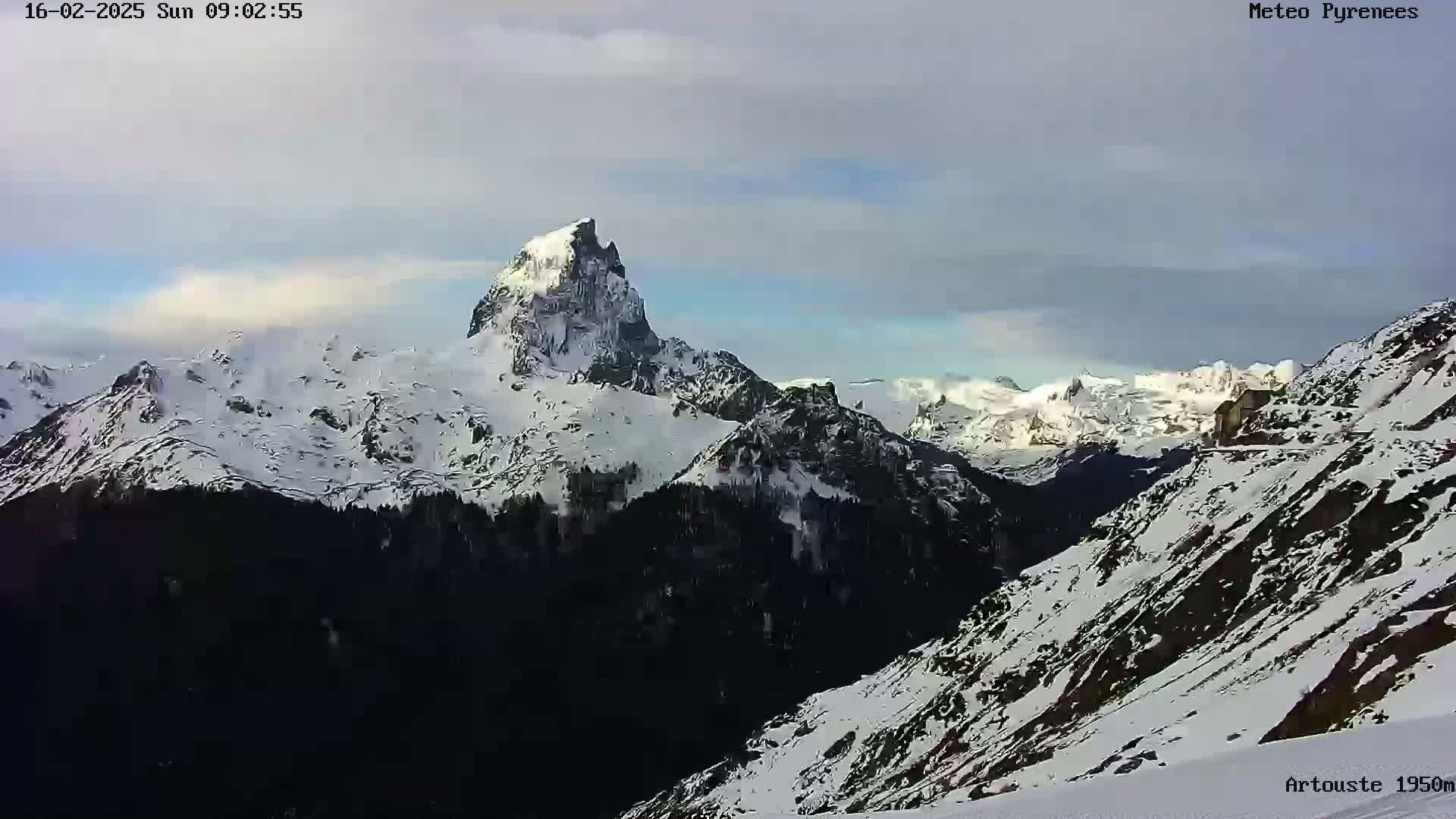 A snow-covered mountain range is visible under a partly cloudy sky.