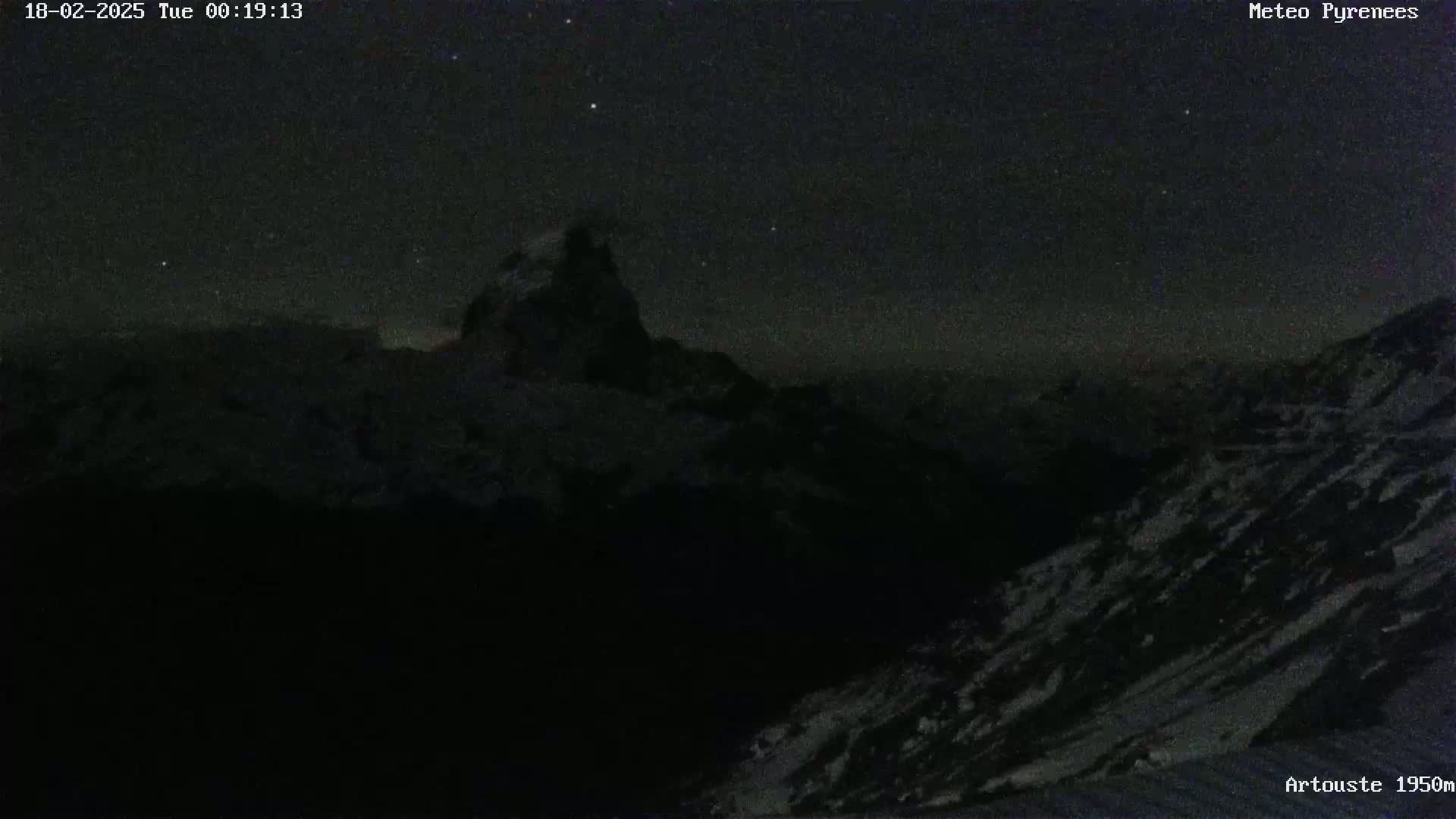 A snow-covered mountain peak is visible under a dark, clear night sky with some stars.