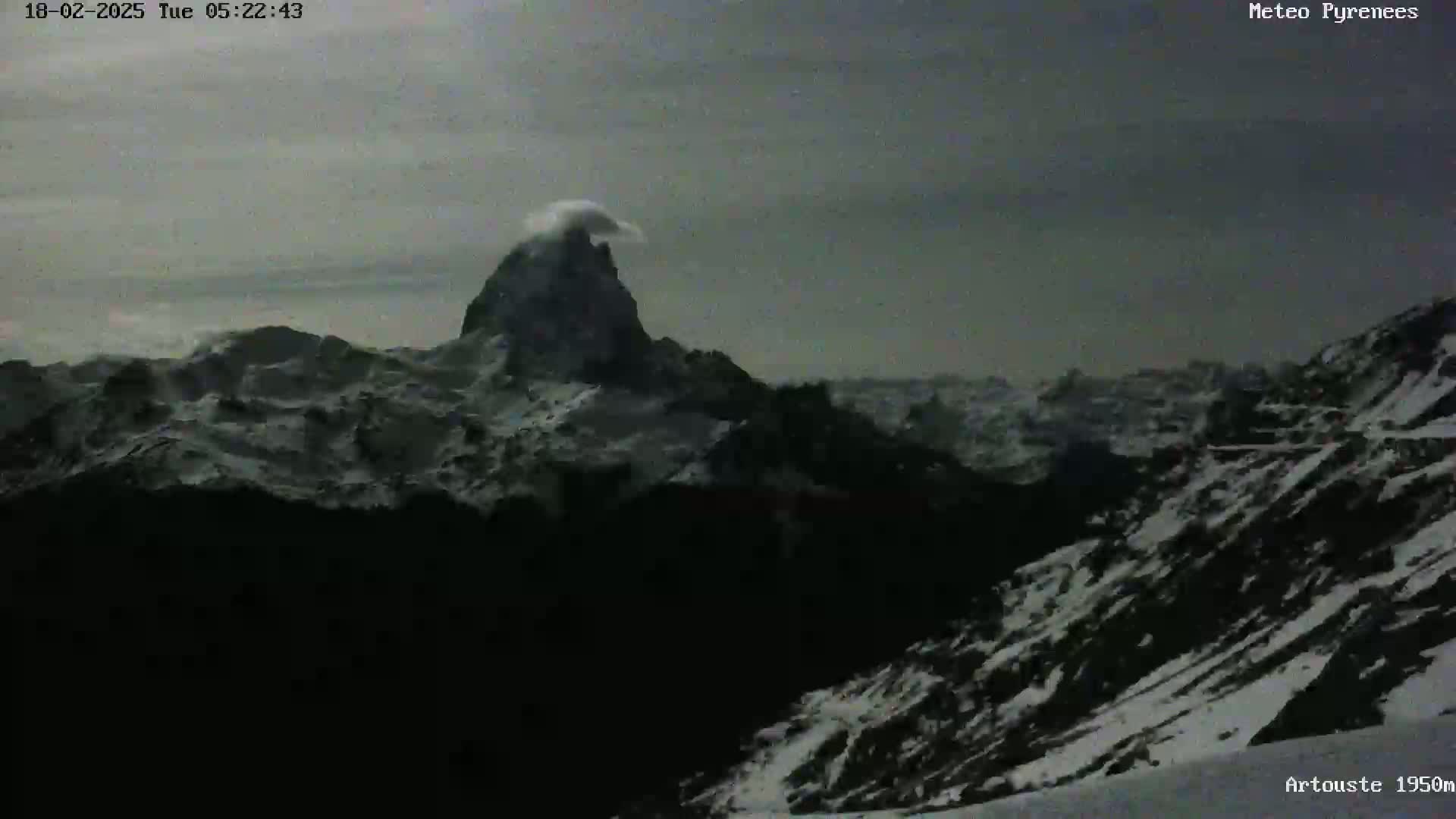 A snow-covered mountain range is visible under a cloudy, overcast sky.