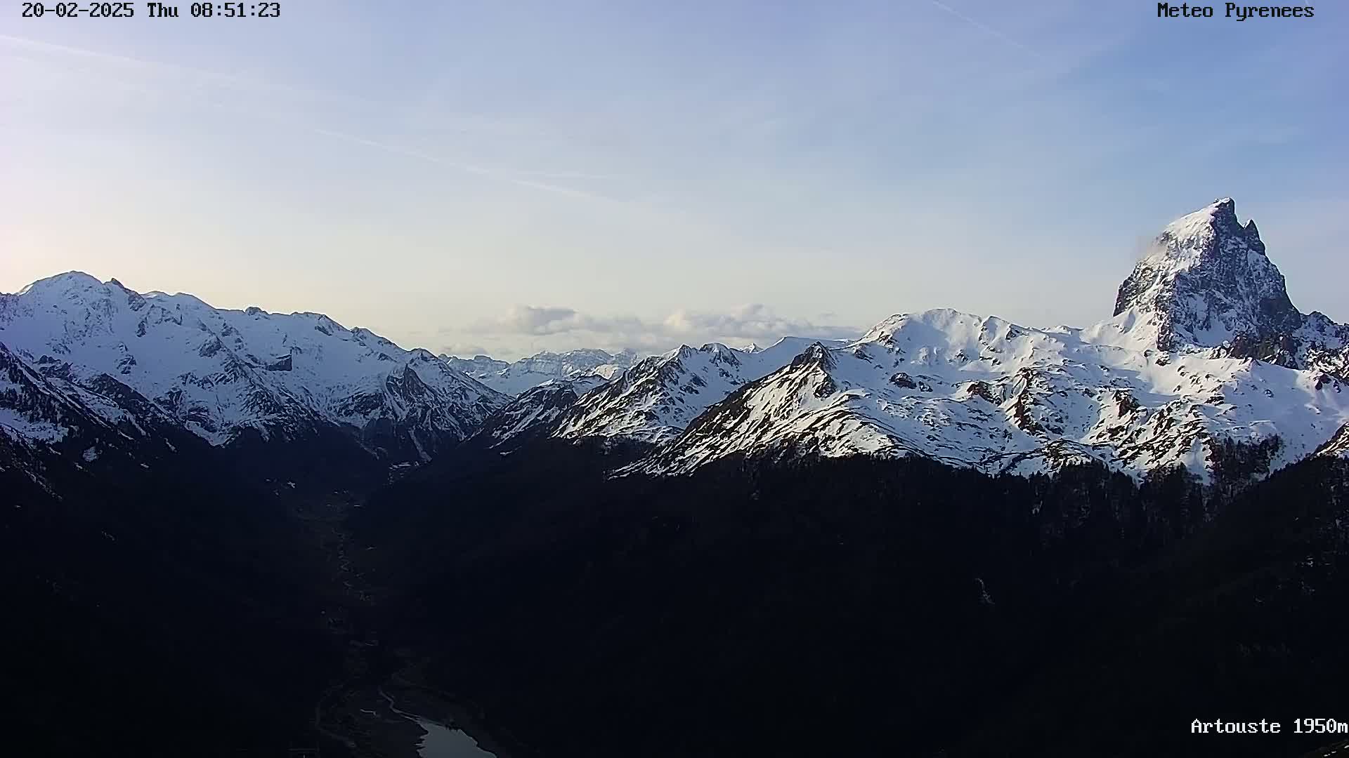 A snow-capped mountain range is visible under a mostly clear, pale blue sky.