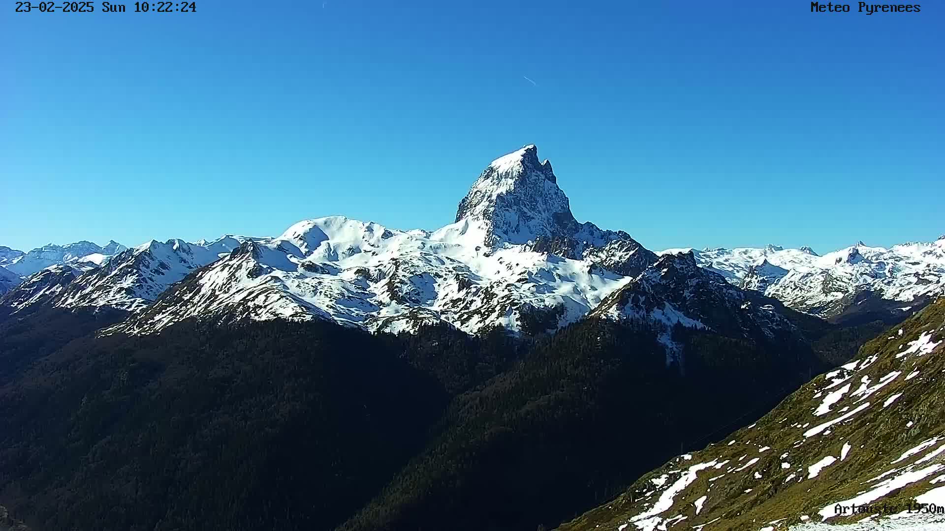A snow-capped mountain range is visible under a clear blue sky.