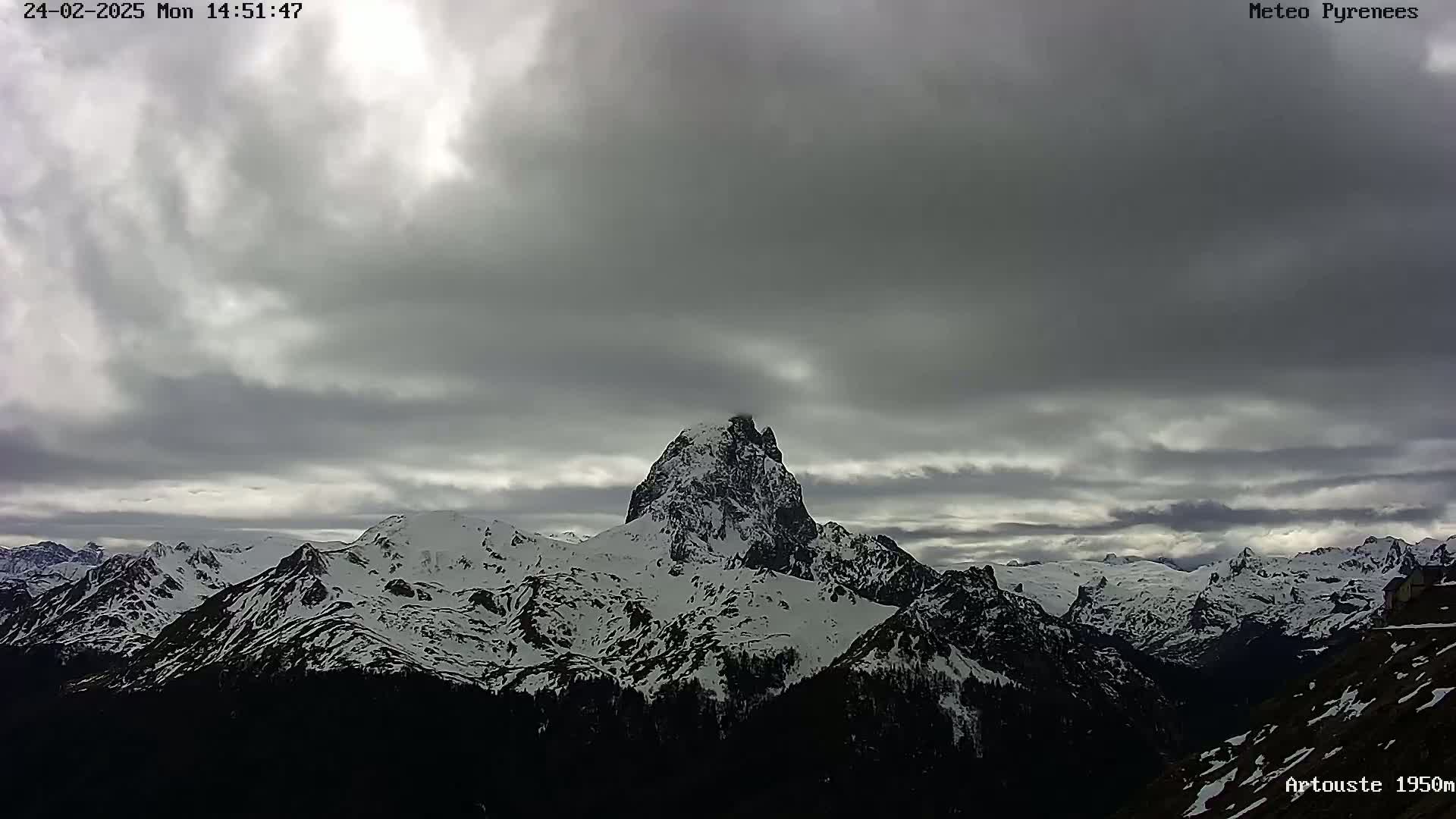 A snow-capped mountain range is visible under a mostly cloudy sky.