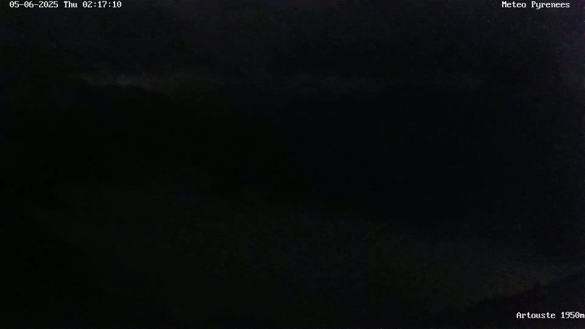 A dark, nighttime image shows a faintly visible, low-lying horizon line against a mostly black sky.